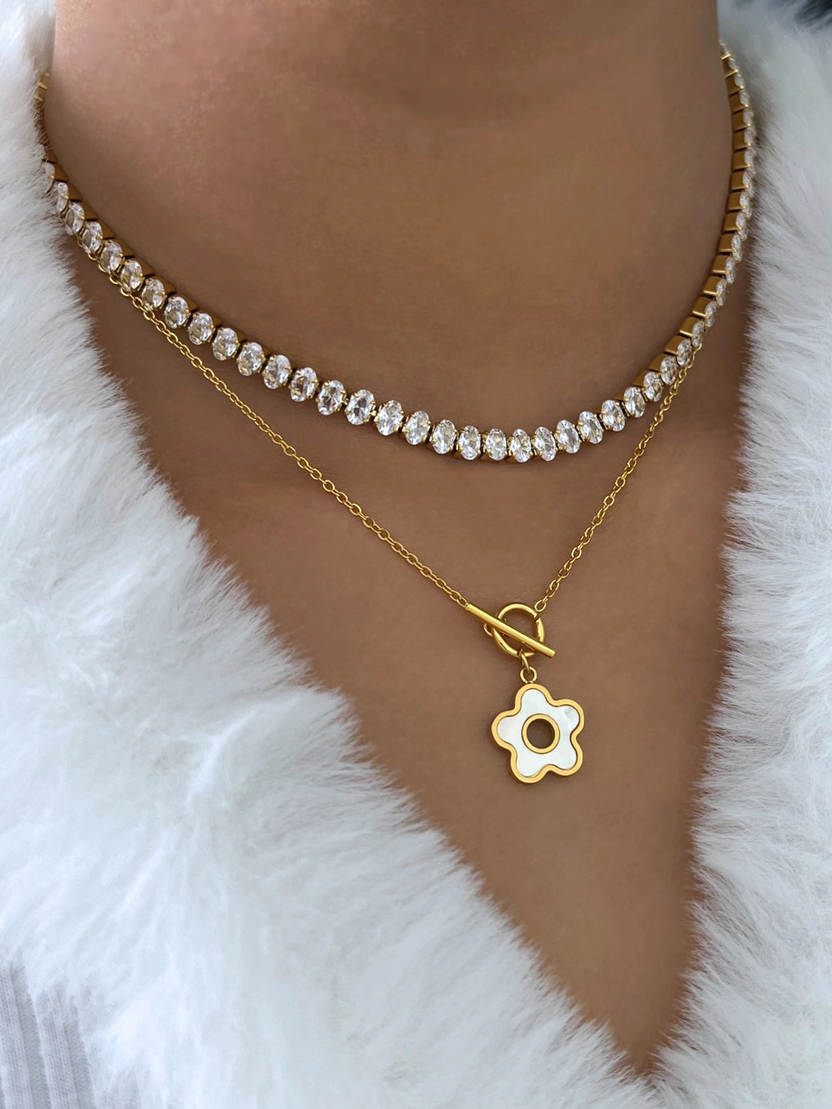 Aria Flower Necklace – On Model Styled Shot-Gold necklace with a flower pendant on a white fur background