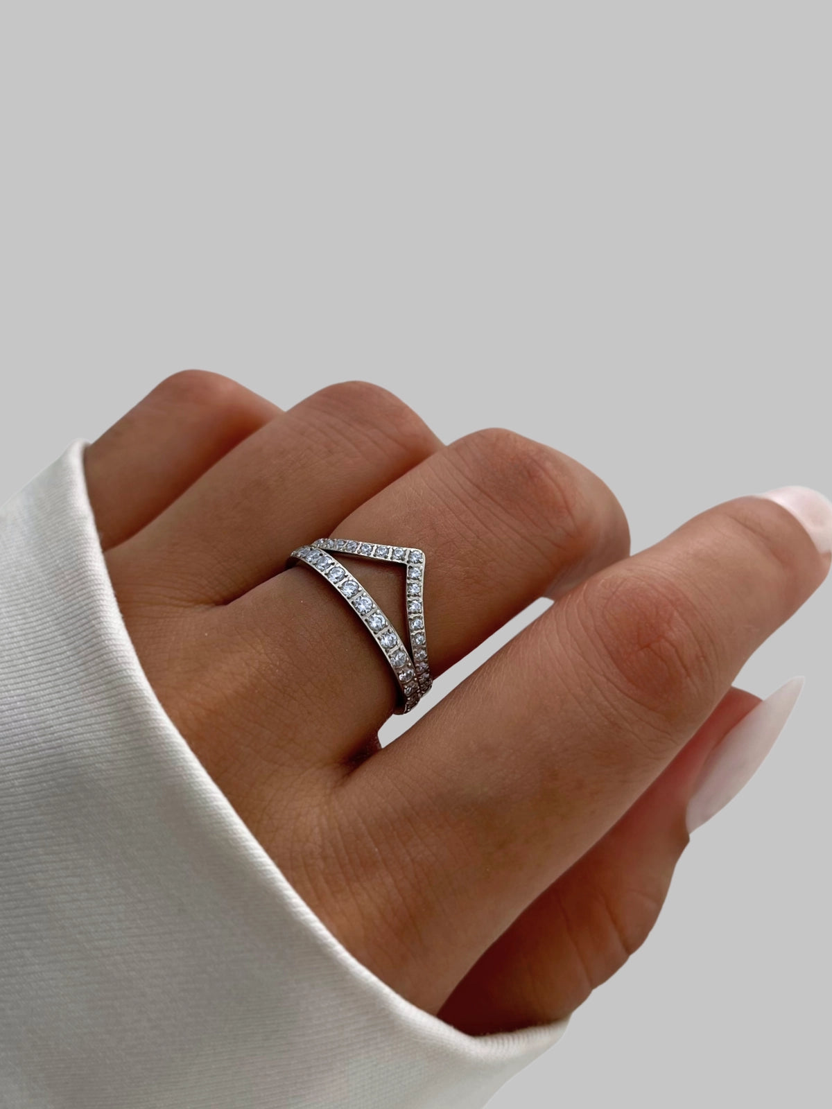 Camille Ring Hand wearing a diamond ring on a plain background