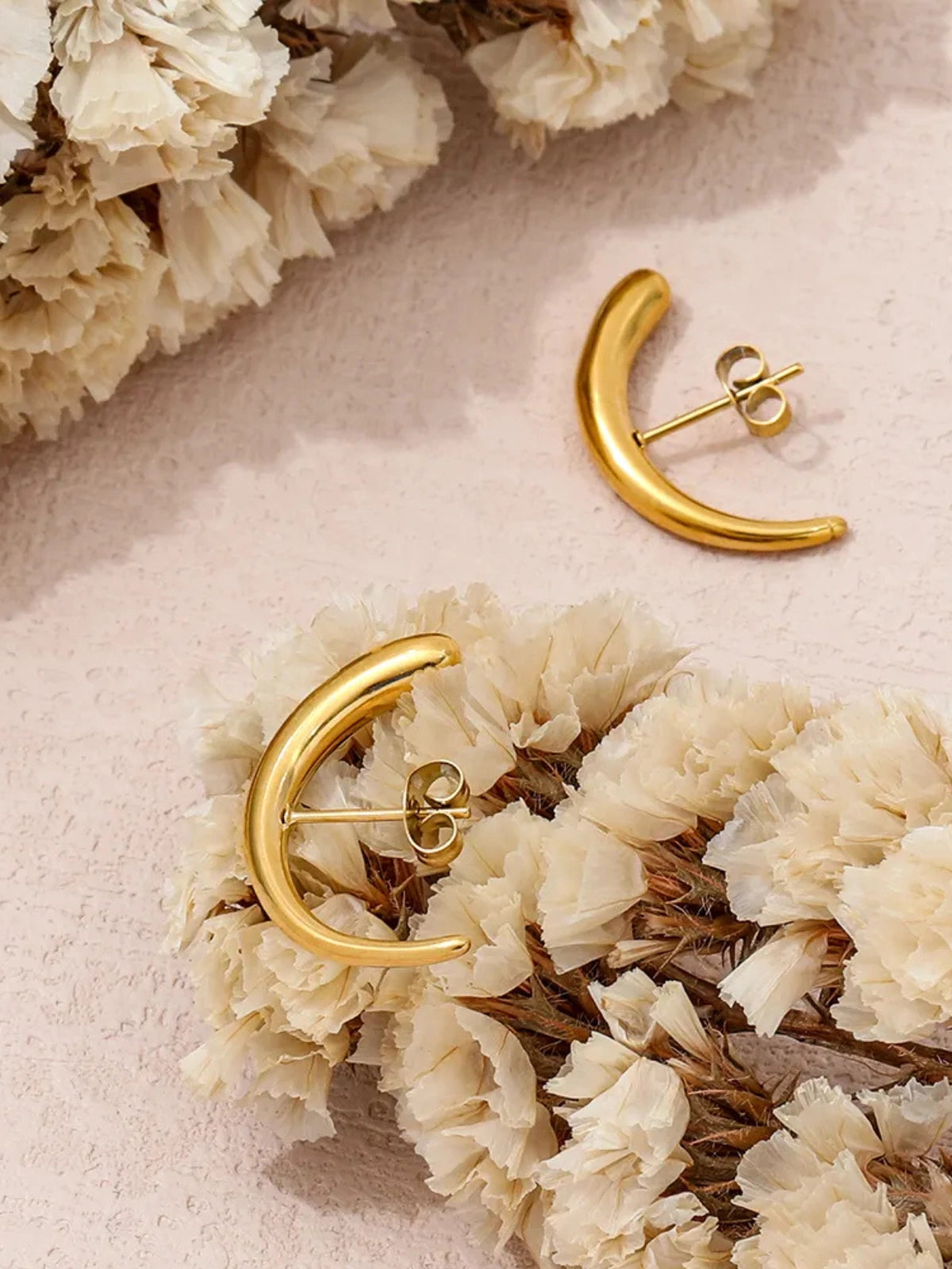 Celora Earring – Close‑Up Detail-Gold earrings on a bed of white flowers