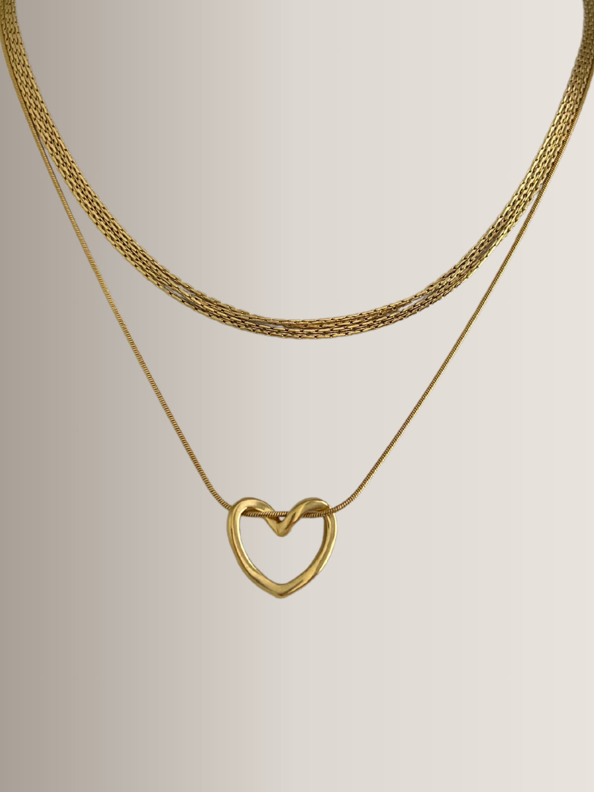 Darla Heart Necklace – Close‑Up Detail-Gold heart-shaped necklace on a light gray background