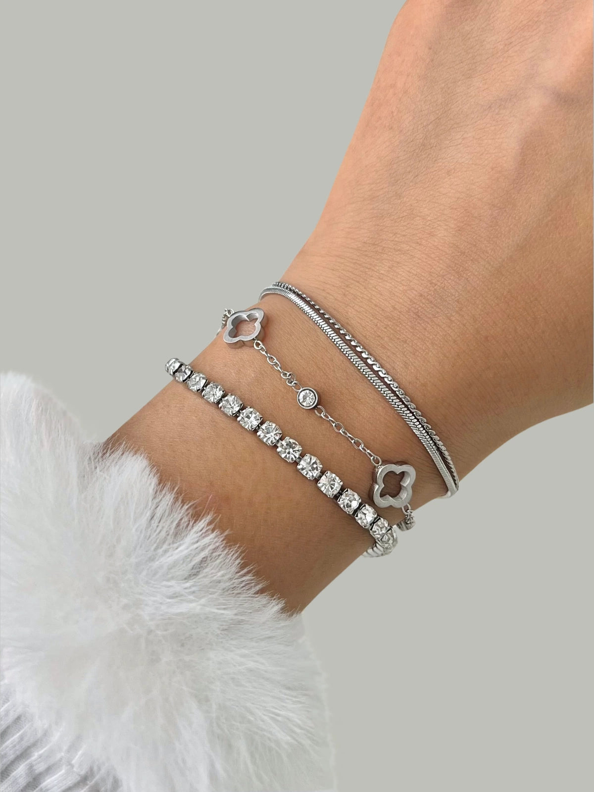 Dua Layered Bracelet – Close-Up-Style-Silver bracelet with clover charms on a wrist against a neutral background
