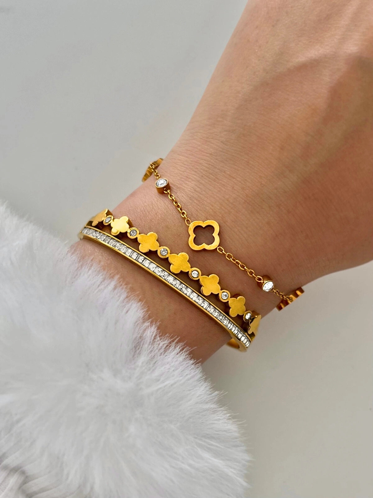 Elle Clover Bracelet – On Wrist, Gold bracelet with clover and pearl designs on a wrist against a white background