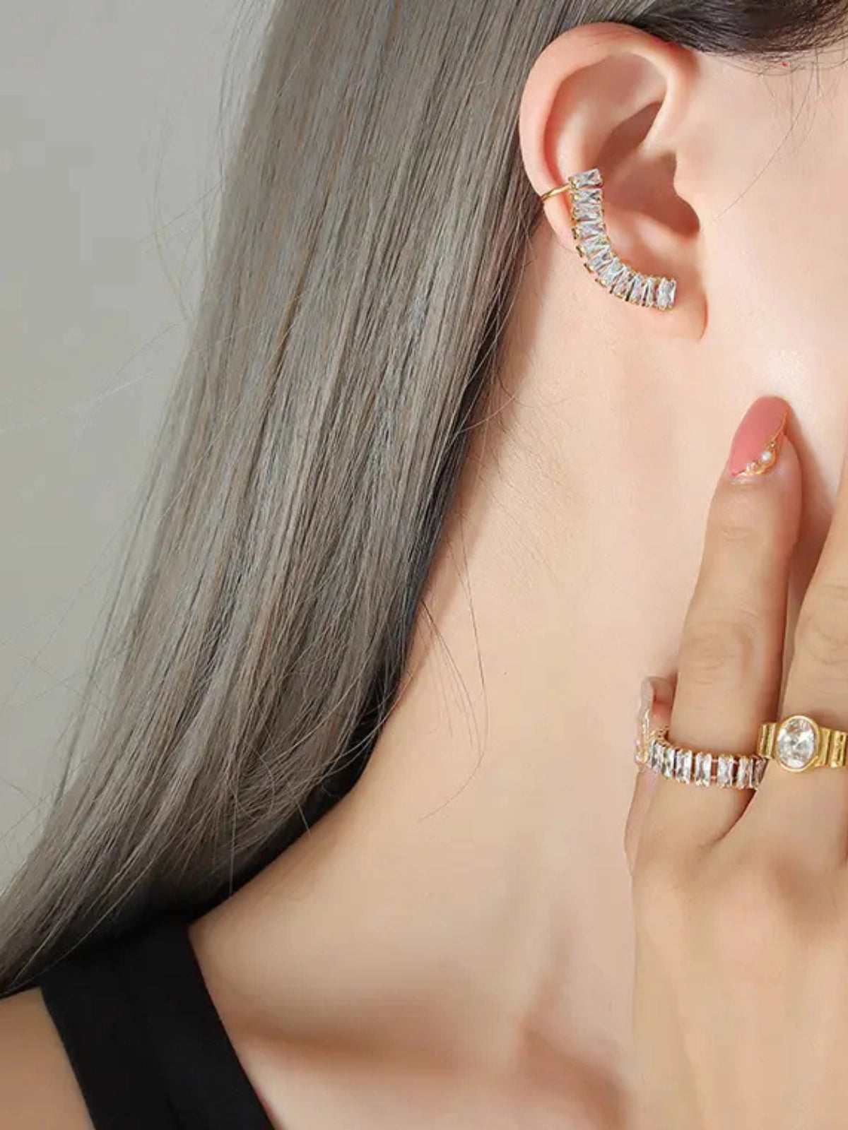 Elly Earring & Cuff – On Ear Styled Shot-Close-up of an ear wearing a diamond earring with a hand holding another diamond ring.