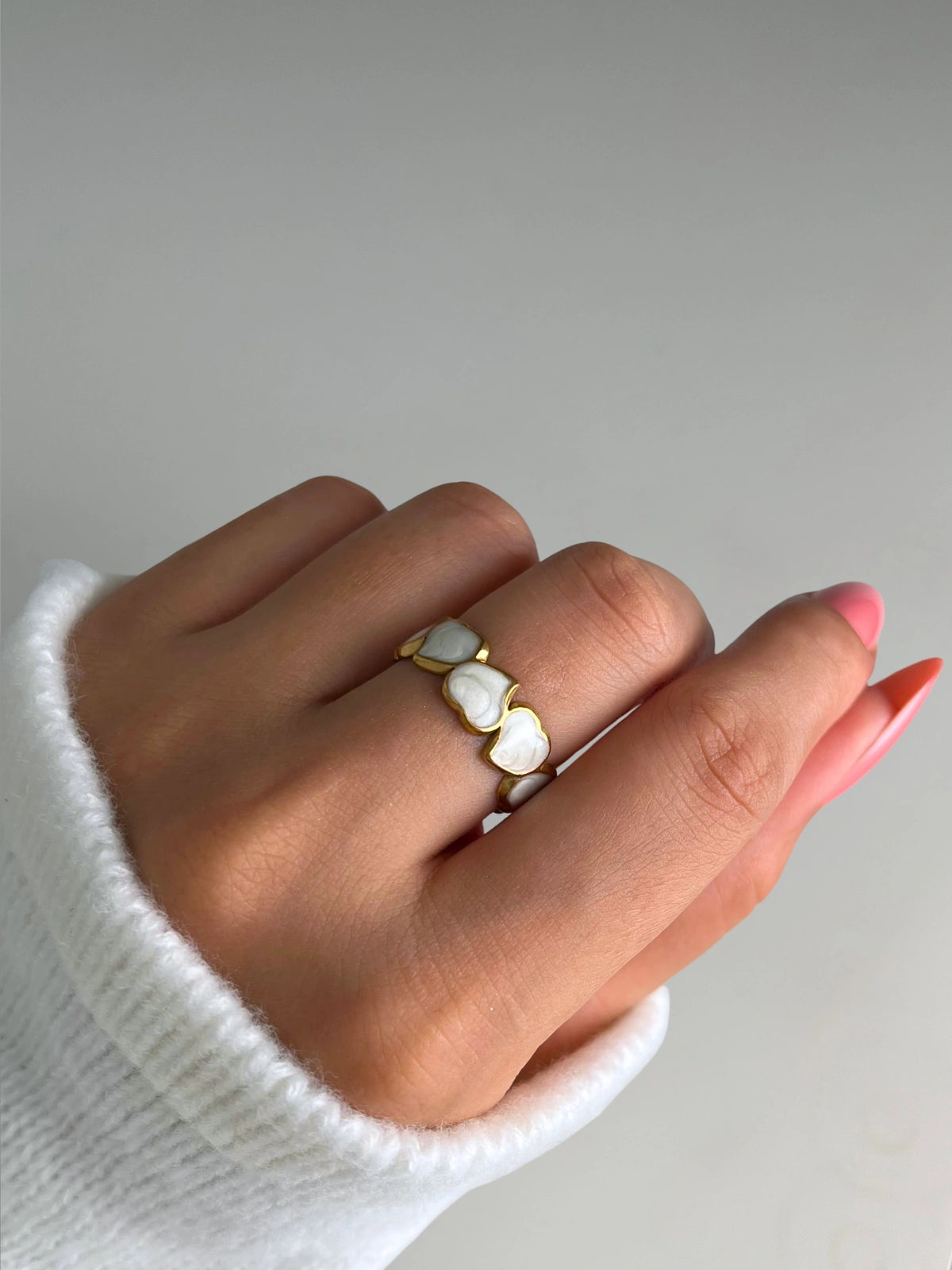 Endless Love Ring – Worn on Finger-Hand wearing a gold ring with white stones on a neutral background