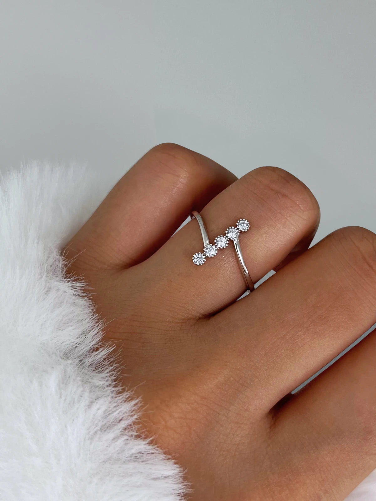 Eva Lane RING Silver ring with three diamonds on a finger against a white background
