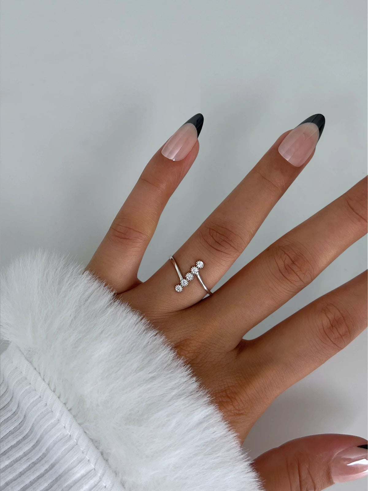 Eva Lane RING Hand wearing a silver ring with small stones on a light gray background