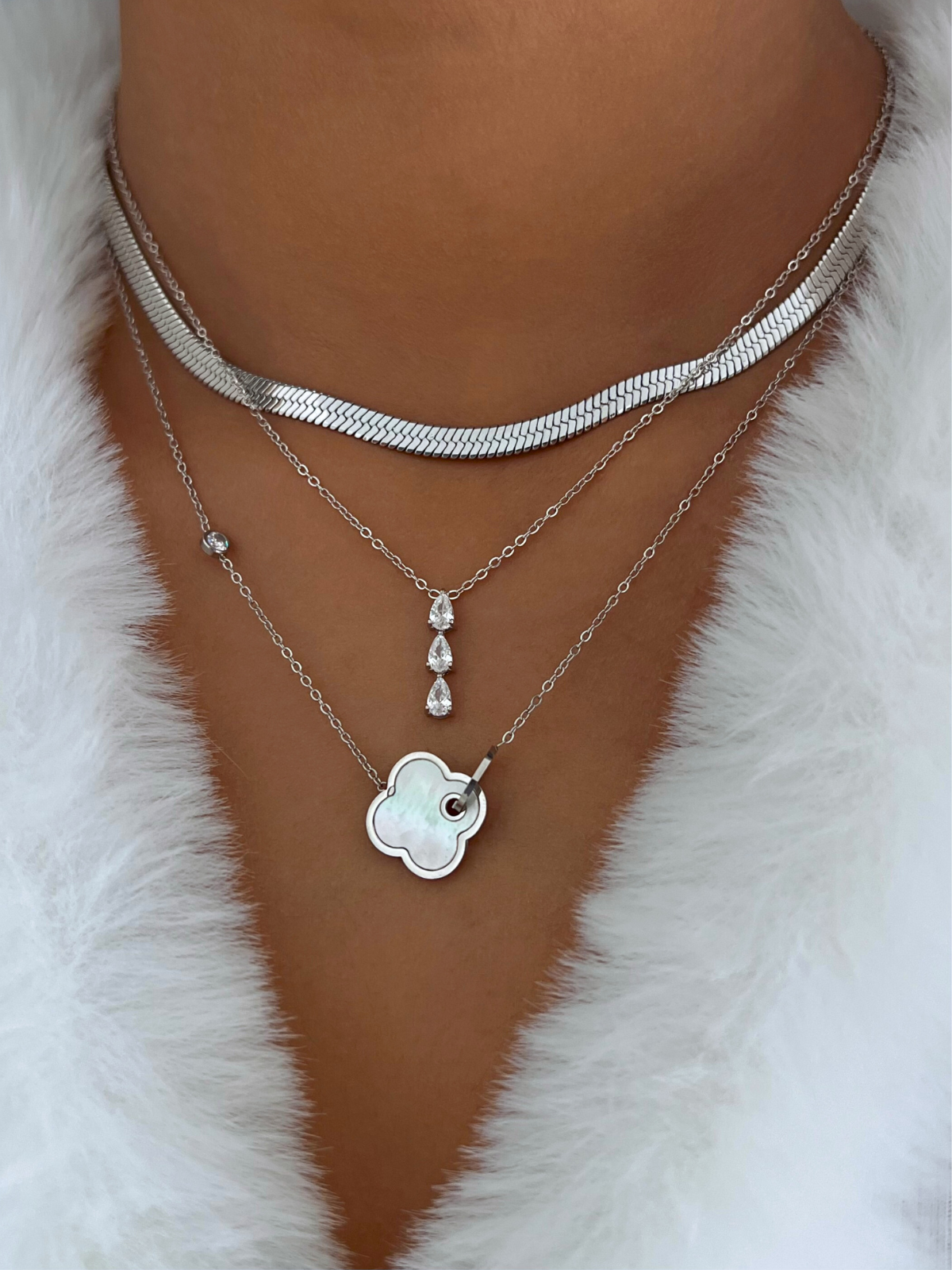 Gina Necklace – On Model Styled Shot-Necklace with cloud pendant and other pendants on a white fur background