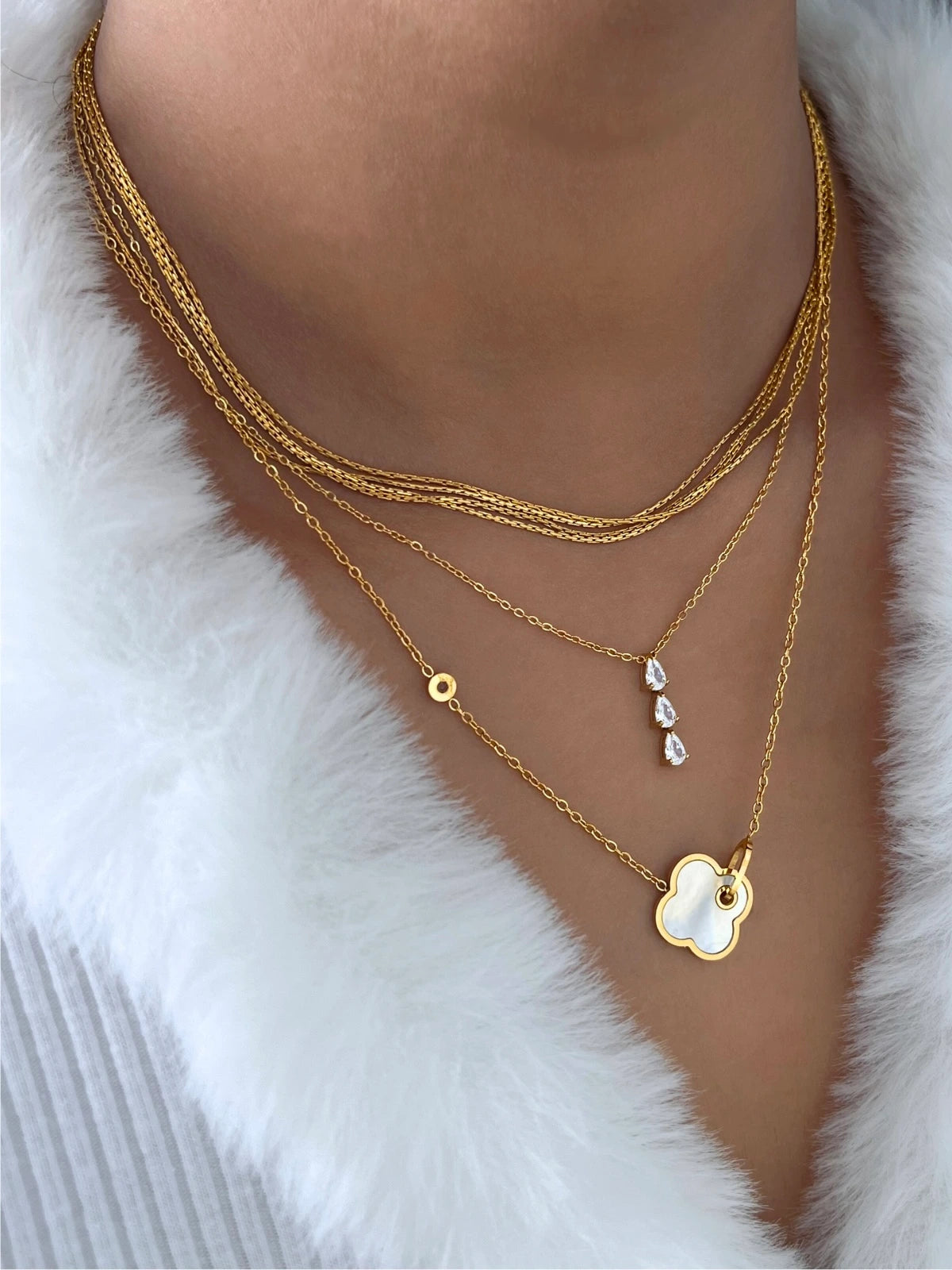 Gina Necklace – On Model Styled Shot-Gold necklaces with heart-shaped pendant on a white fur background
