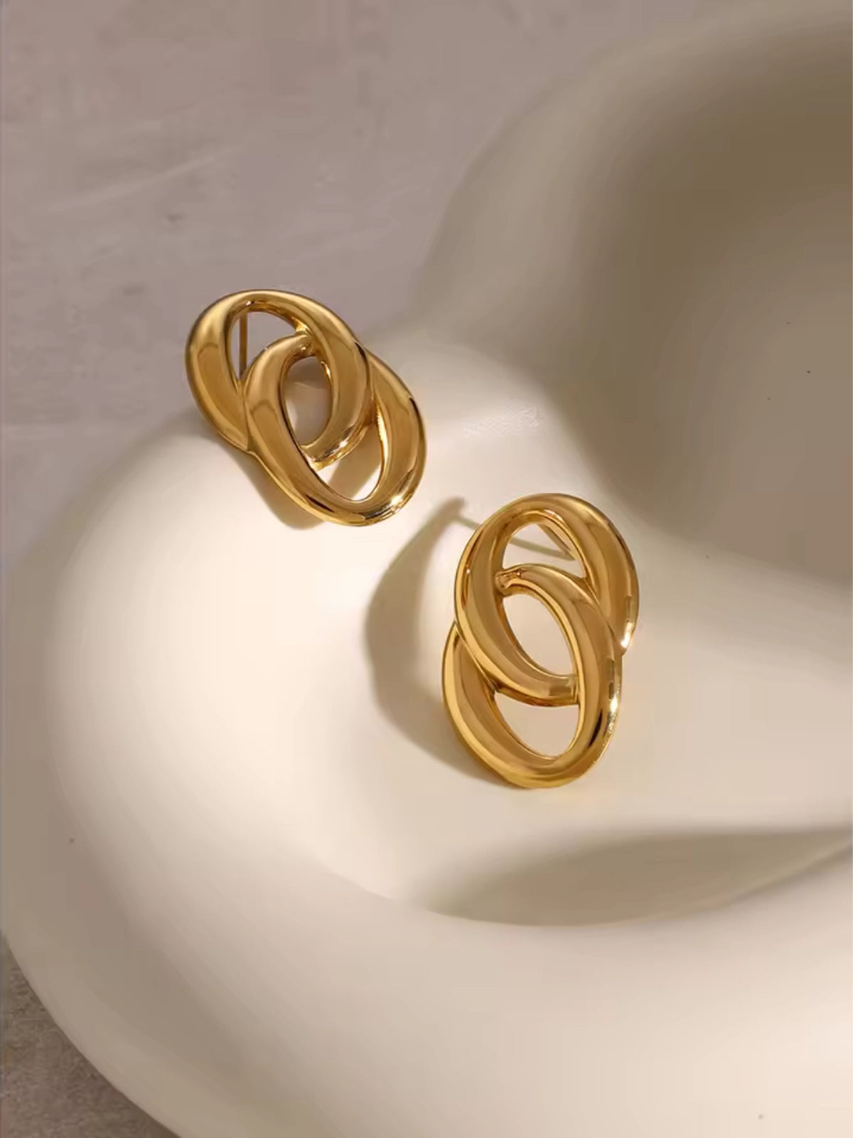 Gomez Earring – Close‑Up Detail-Gold hoop earrings on a white surface