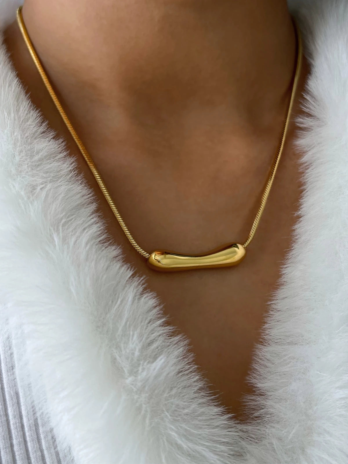 Halia Necklace – On Model Styled Shot-Gold necklace on a person wearing a white fur garment