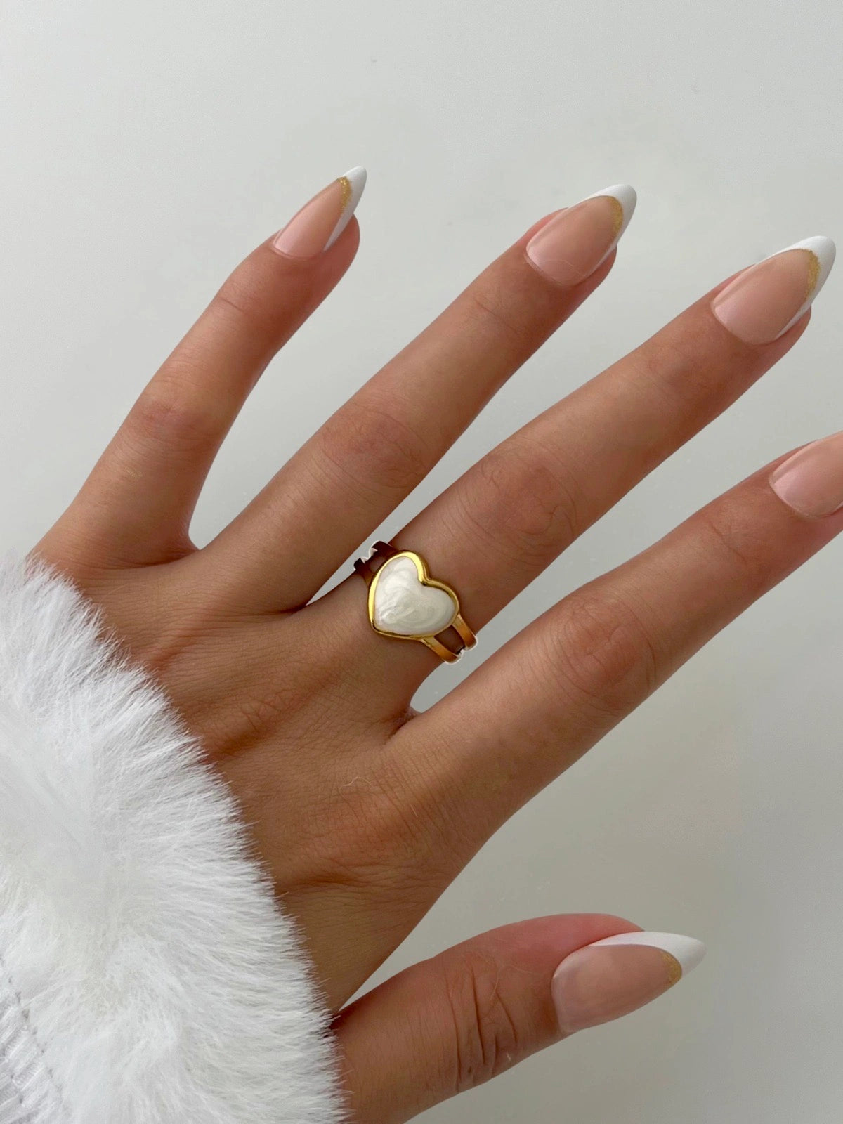 Juliette Ring – Worn on Finger-Hand wearing a heart-shaped ring with a white stone on a plain background