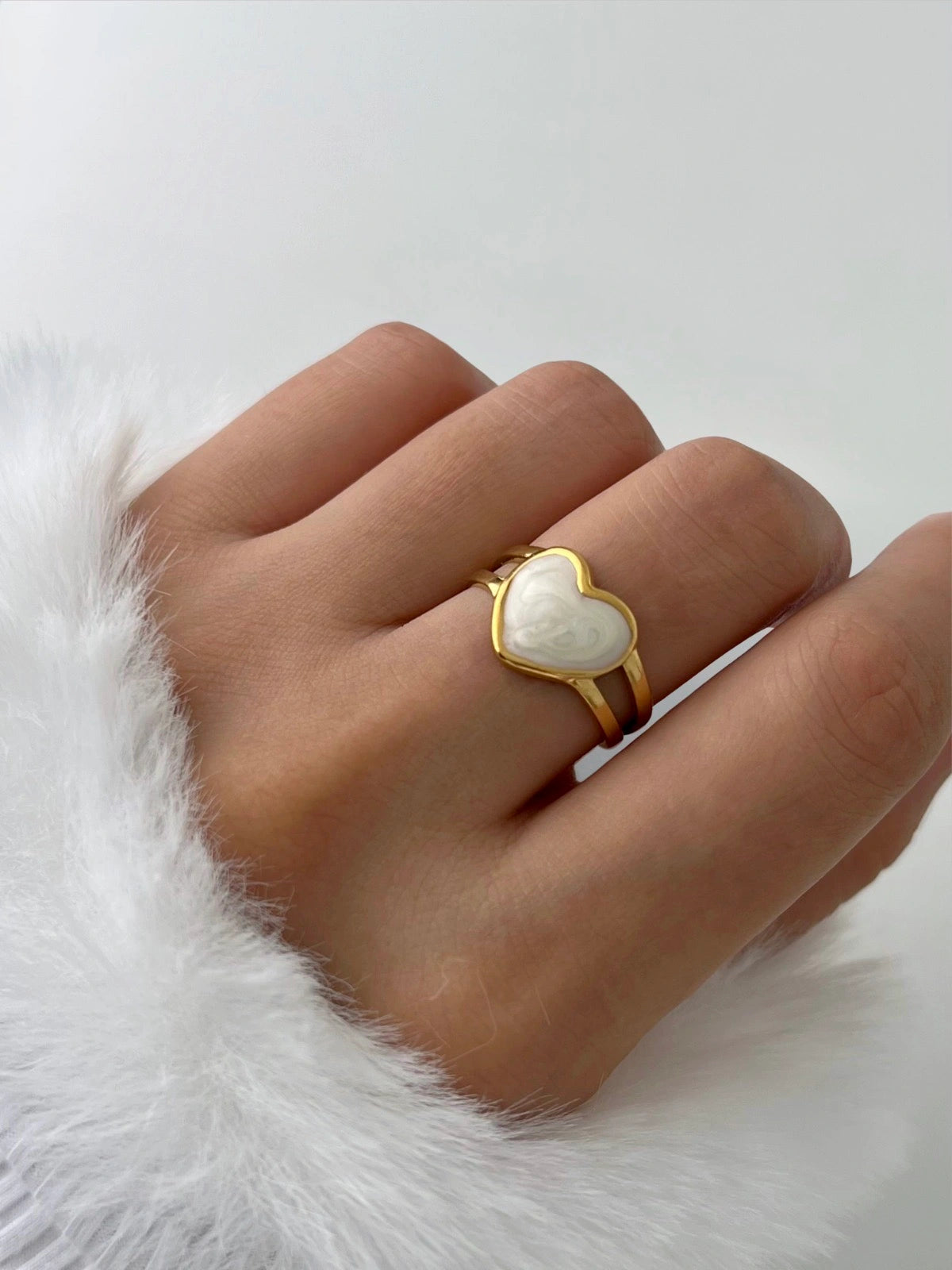 Juliette Ring – Worn on Finger-Gold ring with a heart-shaped gemstone on a hand against a white background