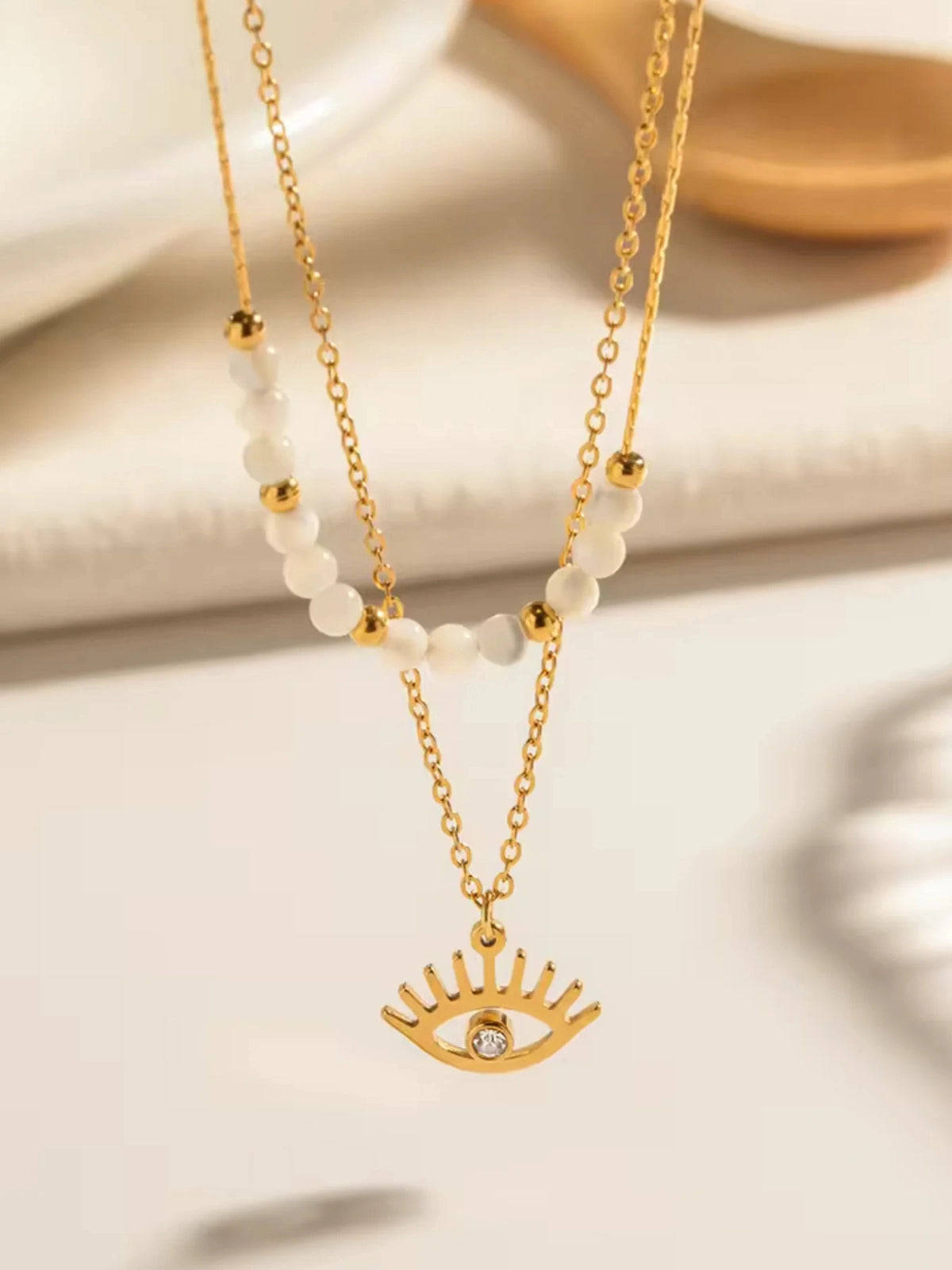 Lume Eye Necklace – Close-Up Detail-Gold necklace with eye-shaped pendant on a light background