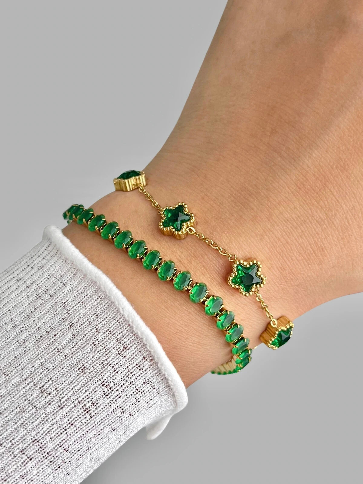 Lunetta Bracelet – Colour Green, Gold bracelet with green gemstones on a wrist against a gray background