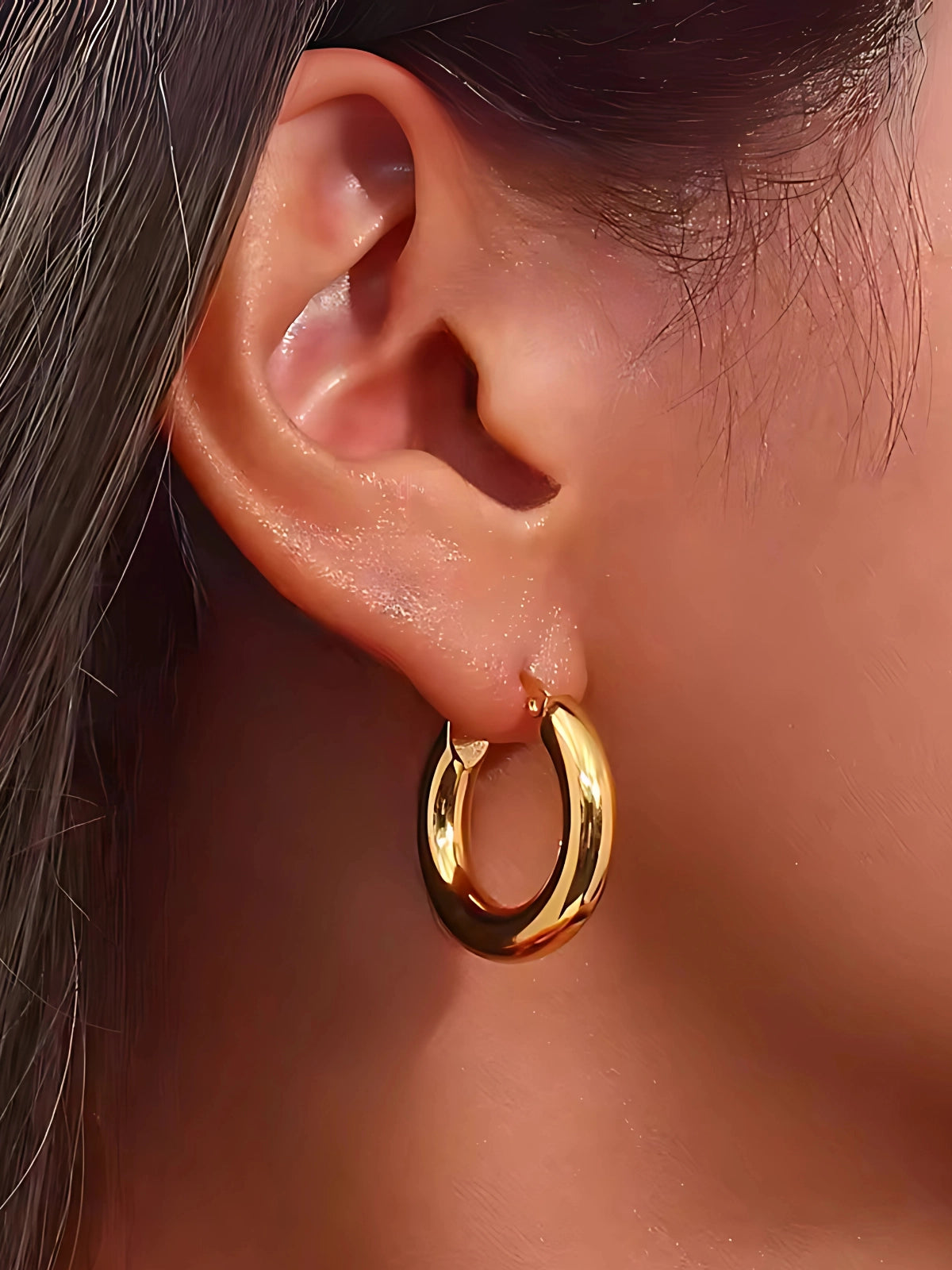Luxe Earring – On Ear Styled Shot-Gold hoop earring worn by a person with dark hair.