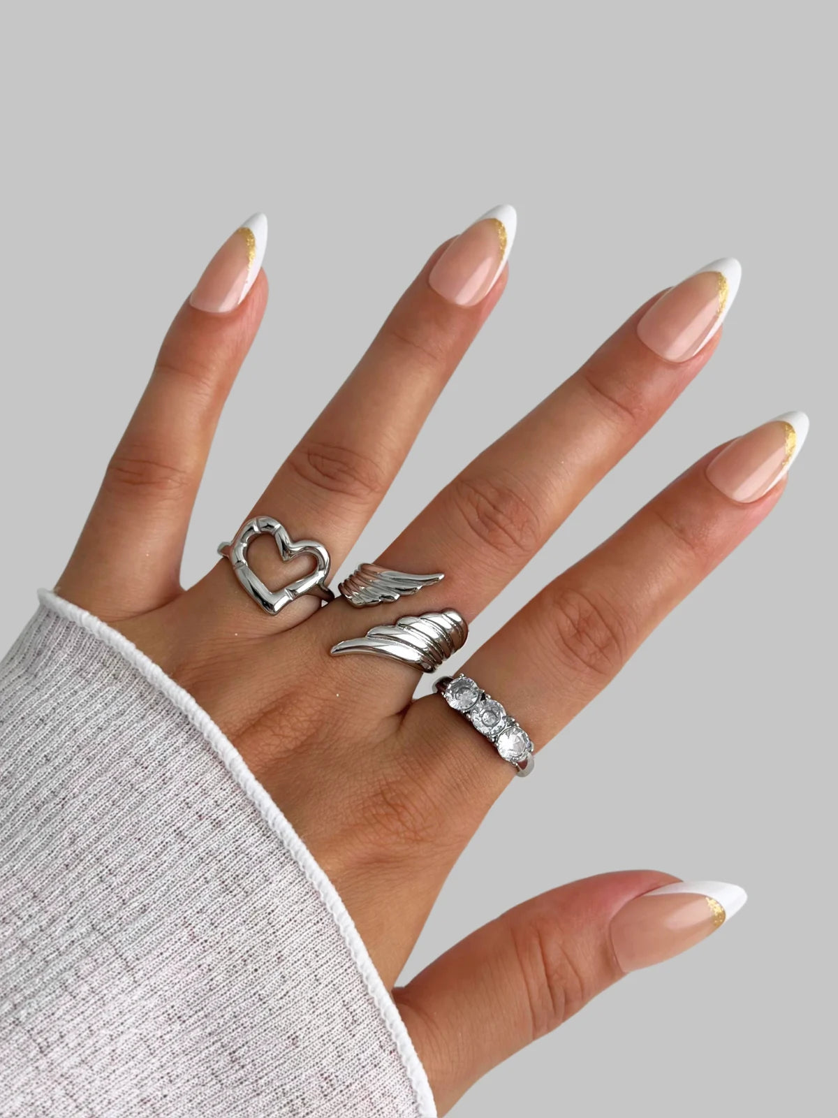 Luxe Ring – Detail in Use-Hand wearing three silver rings with a plain background