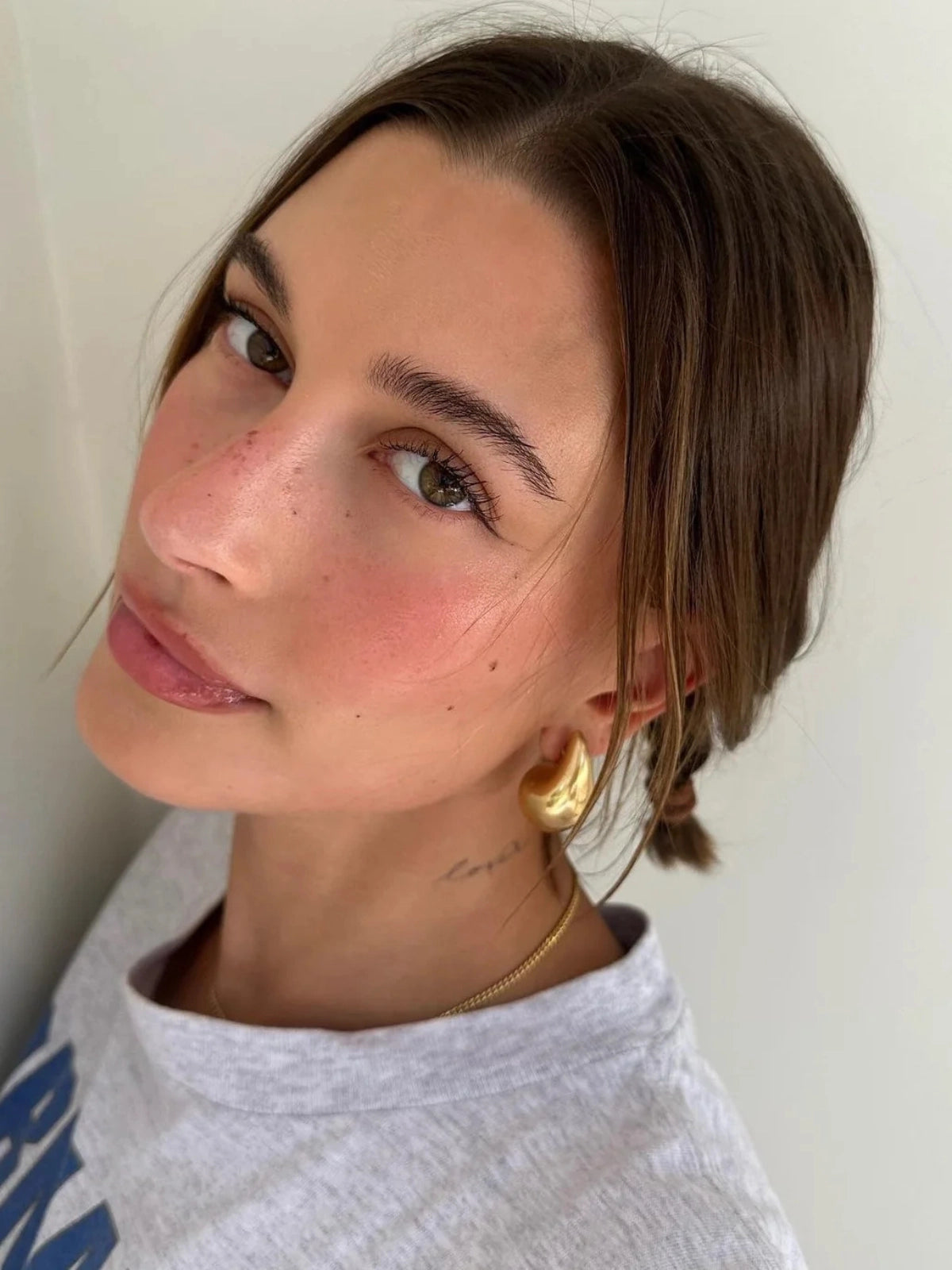 Madonna Drop Earring – On Ear Styled Shot-Woman with braided hair wearing a gold earring and necklace against a plain background