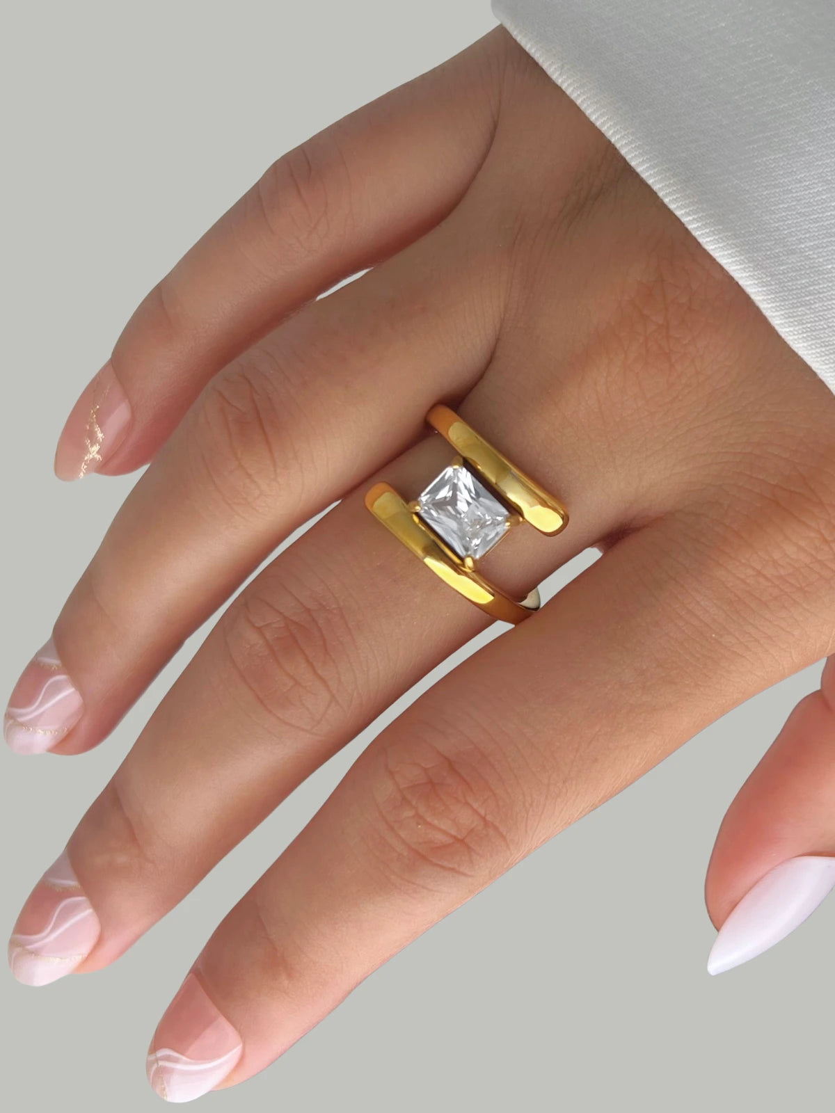 Moonbeam Ring – Lifestyle Look-Gold ring with a diamond on a hand against a neutral background