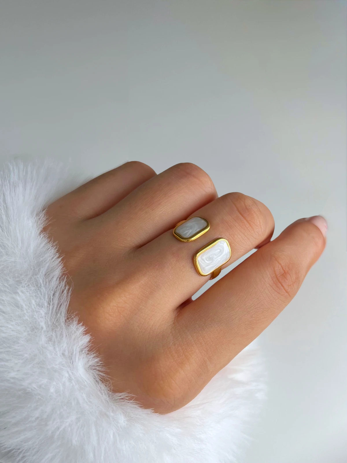 Moonlight Whisper Ring – Worn on Finger-Hand wearing two gold rings with white stones on a white background