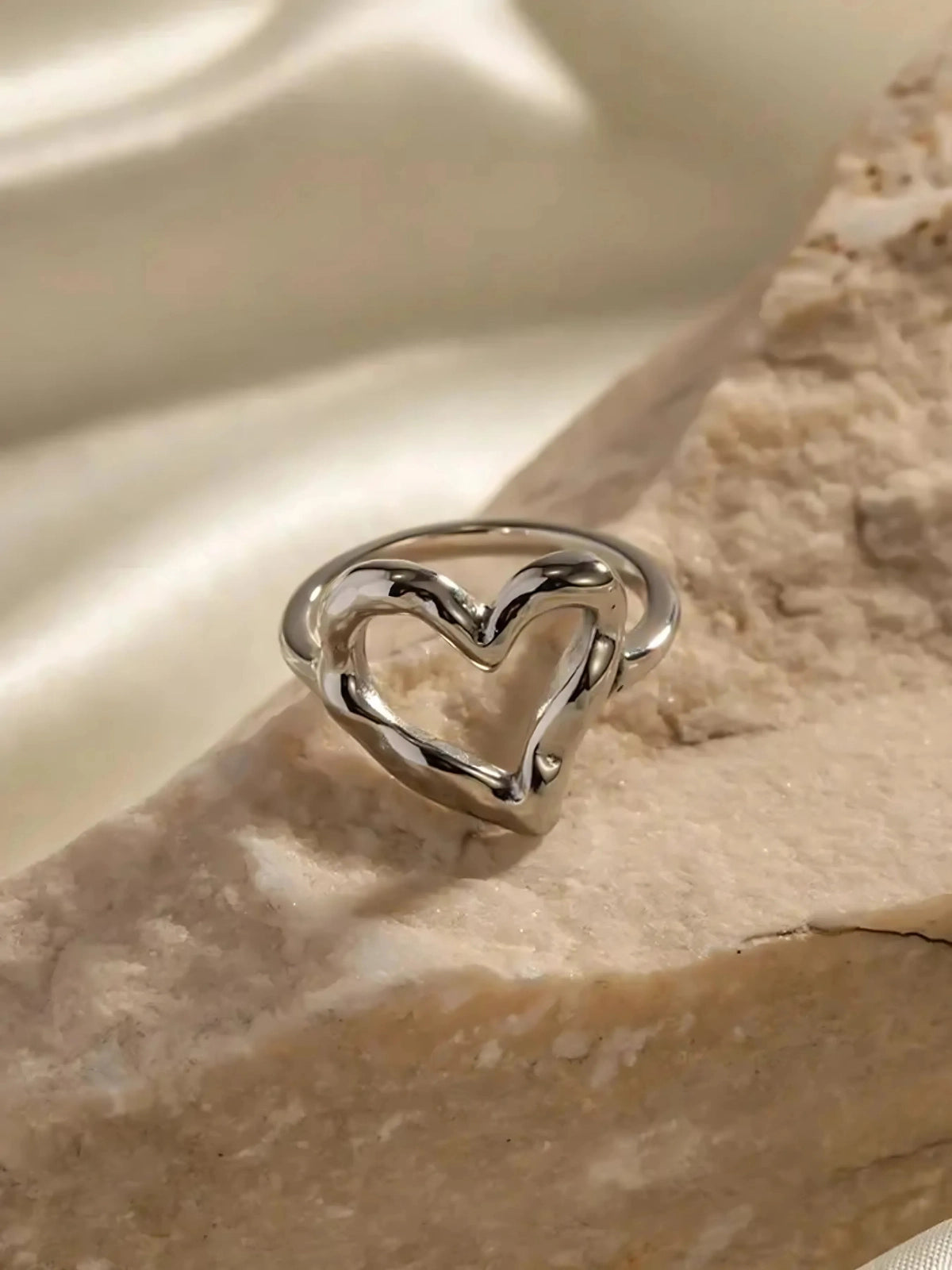 My Heart Loop Ring – Worn on Finger-Silver heart-shaped ring on a textured stone surface