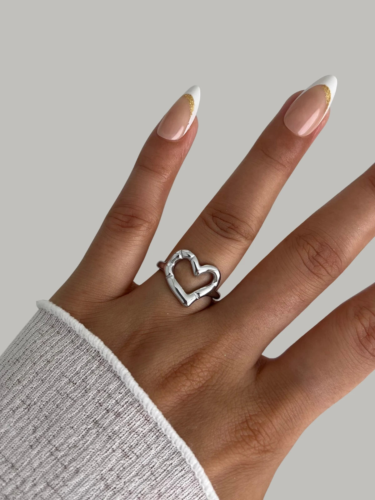 My Heart Loop Ring – Worn on Finger-Hand wearing a silver heart-shaped ring on a neutral background