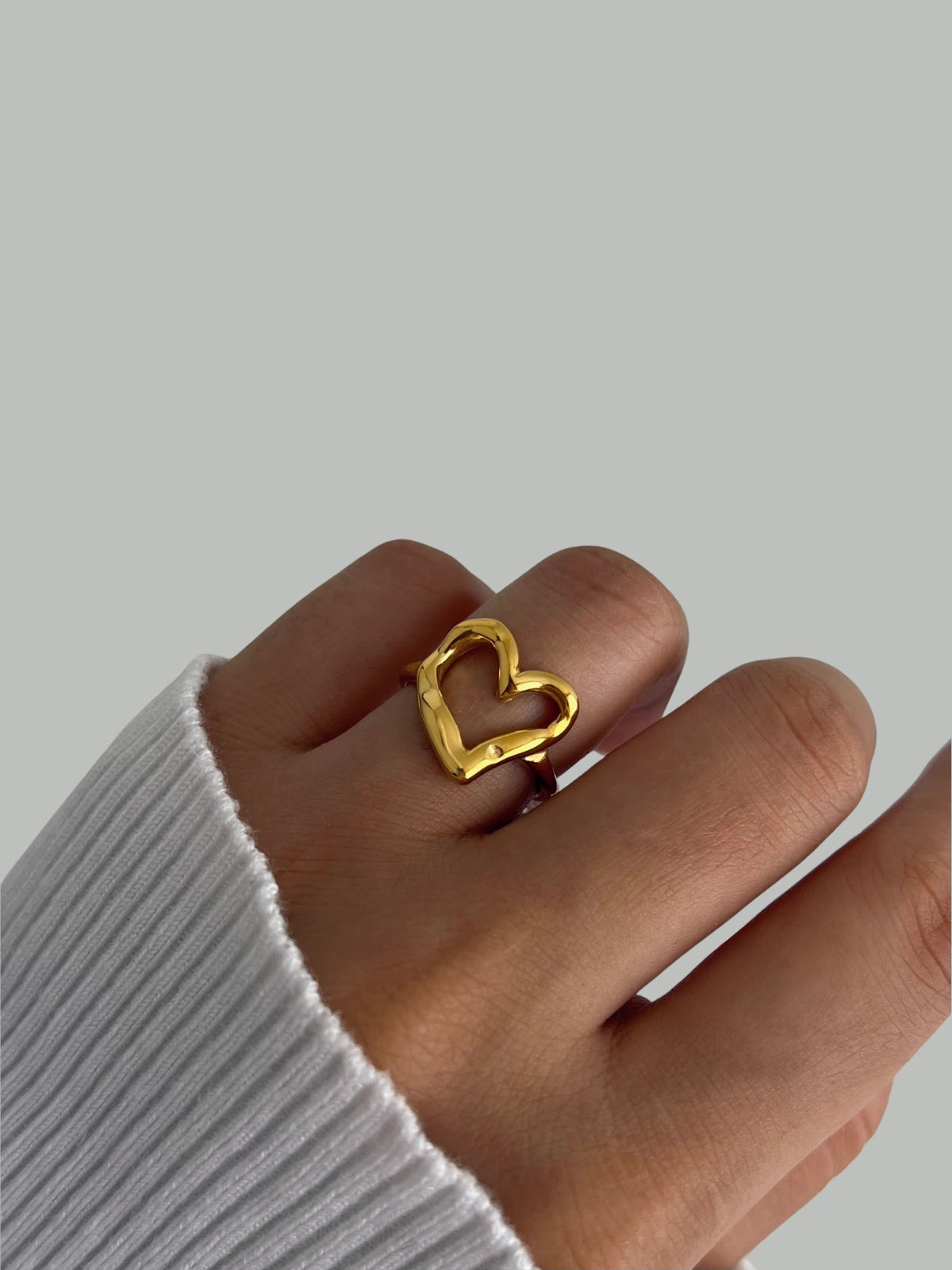 My Heart Loop Ring – Worn on Finger-Gold heart-shaped ring on a hand with a plain background