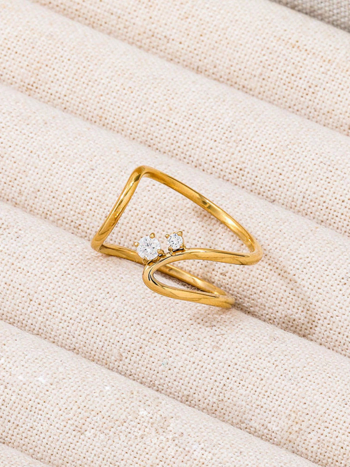 Noelle_Ring_Front_View_1 Gold ring with two diamonds on a beige fabric background