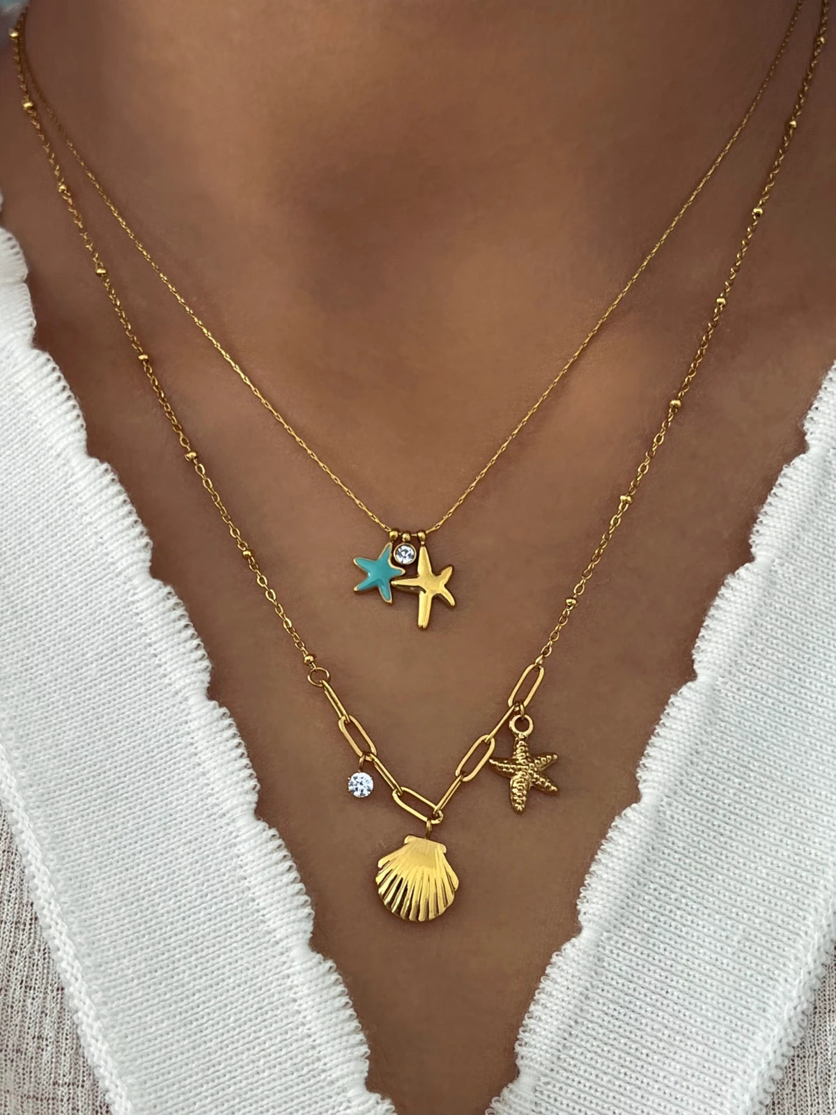 Nova Shell Necklace – On Model Styled Shot-Gold necklace with star and shell charms on a person wearing a white top.