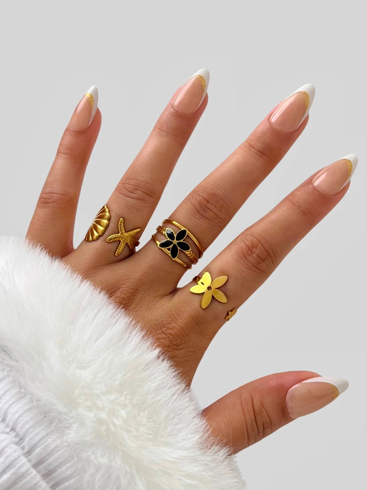 Ocean Embrace Ring. Hand wearing multiple rings with decorative designs on a light background