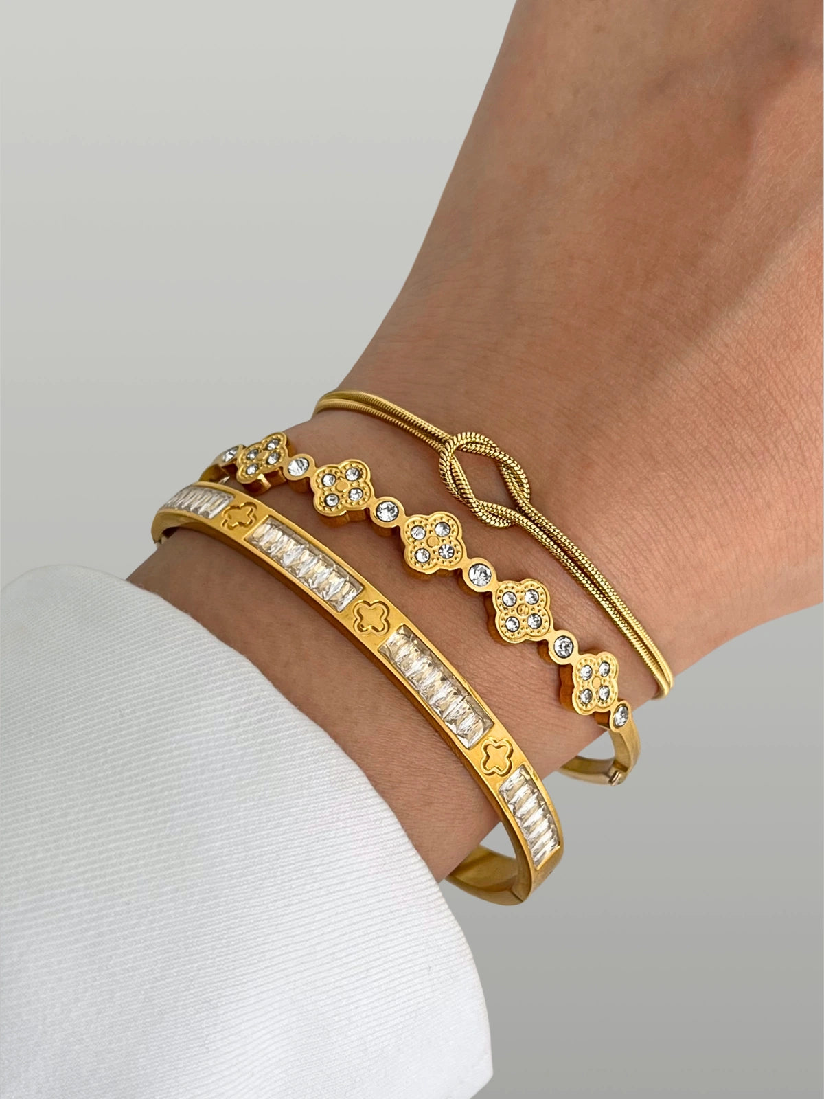 Opal clover bangle Gold with intricate designs on a wrist against a neutral background