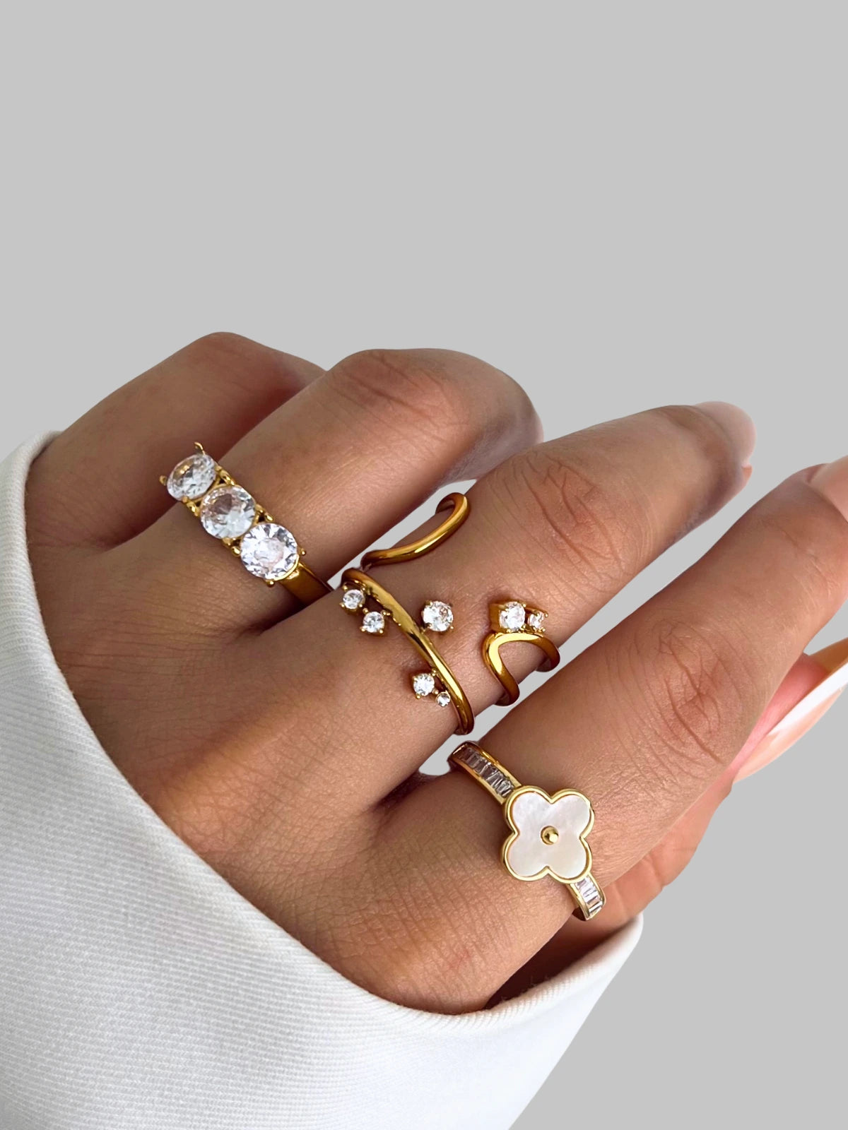 Pearl Bloom Ring – On Model Styled Shot-Hand wearing multiple gold rings with different designs on a neutral background