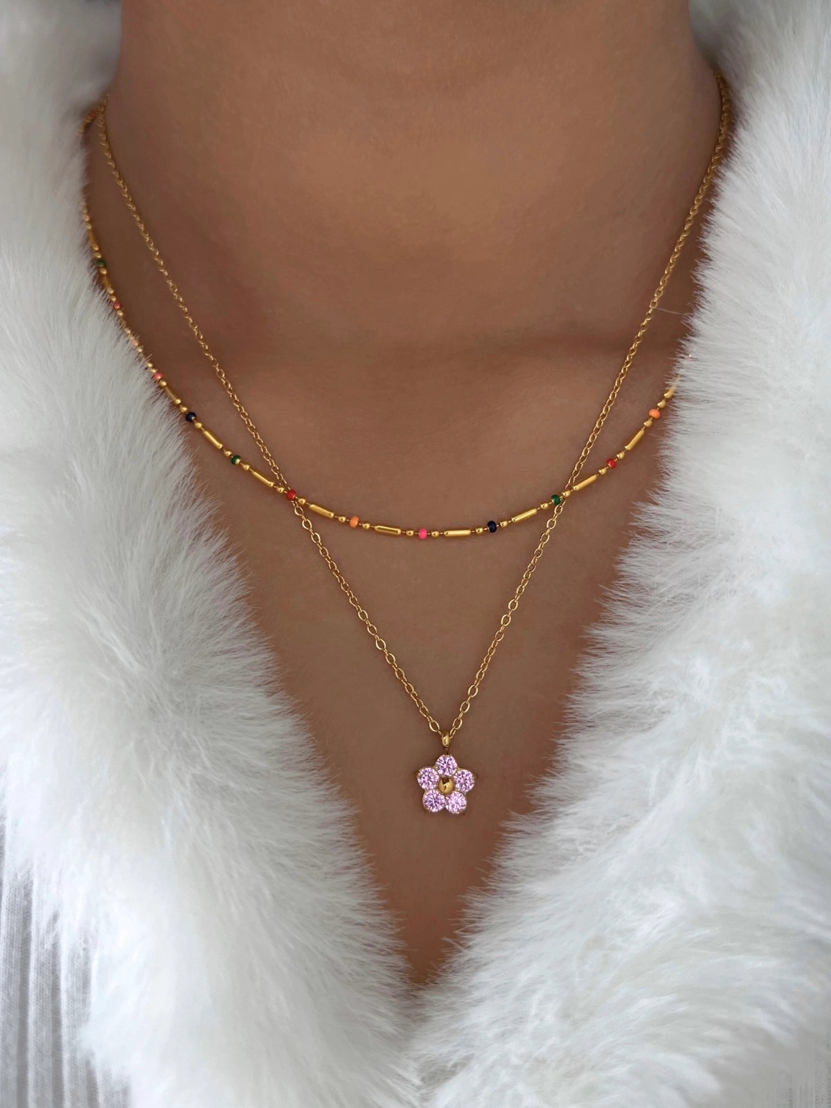 Petalia Necklace – Close-Up Detail-Gold necklace with a pink flower pendant on a white fur background