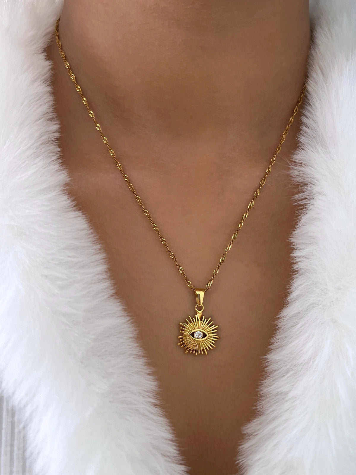 Rawah Necklace & RING-Gold necklace with a pendant worn by a person against a white fur background
