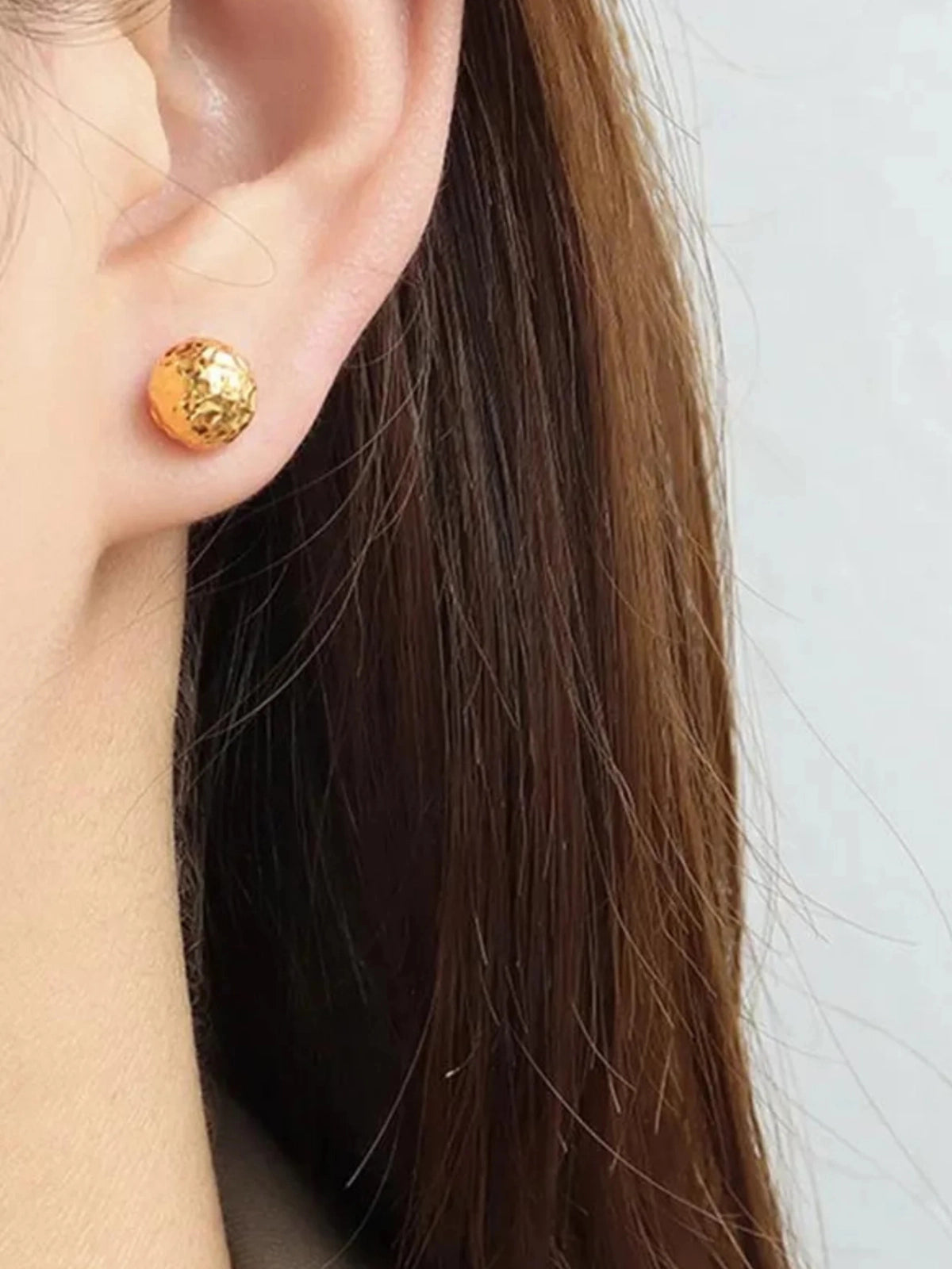 Raya Stud Earring – On Ear Styled Shot-Gold stud earring worn by a person with long brown hair on a white background