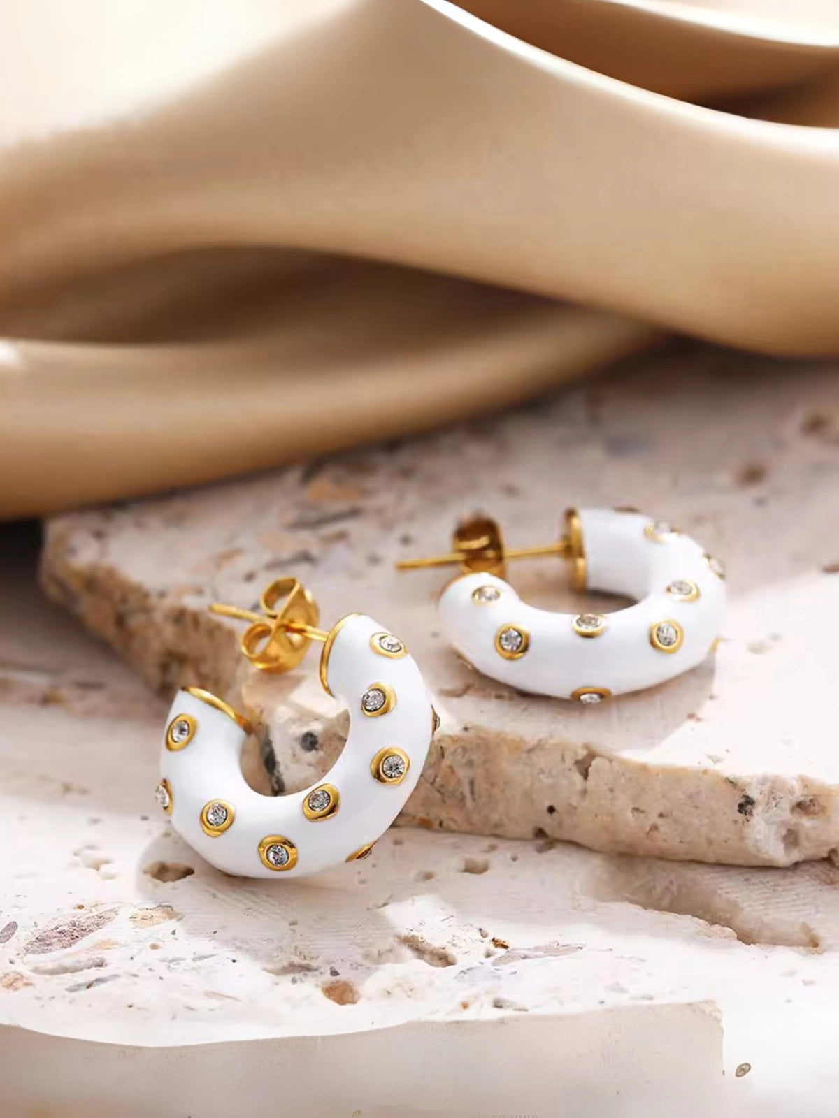 Royal Hoop Earring – Close‑Up Detail-White hoop earrings with gold accents on a textured surface