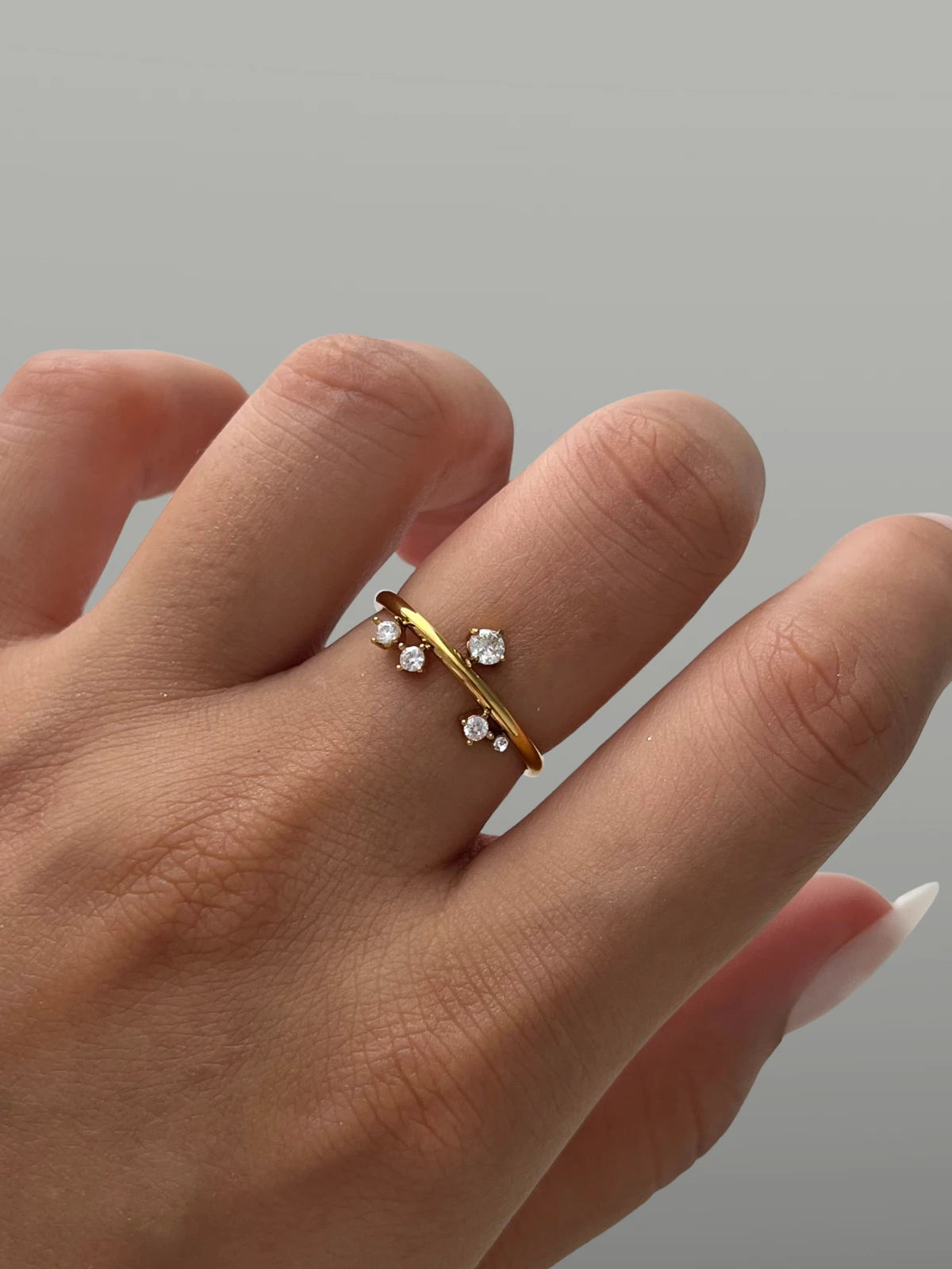 Sandrine Ring – Worn on Finger-Gold ring with small diamonds on a finger against a neutral background
