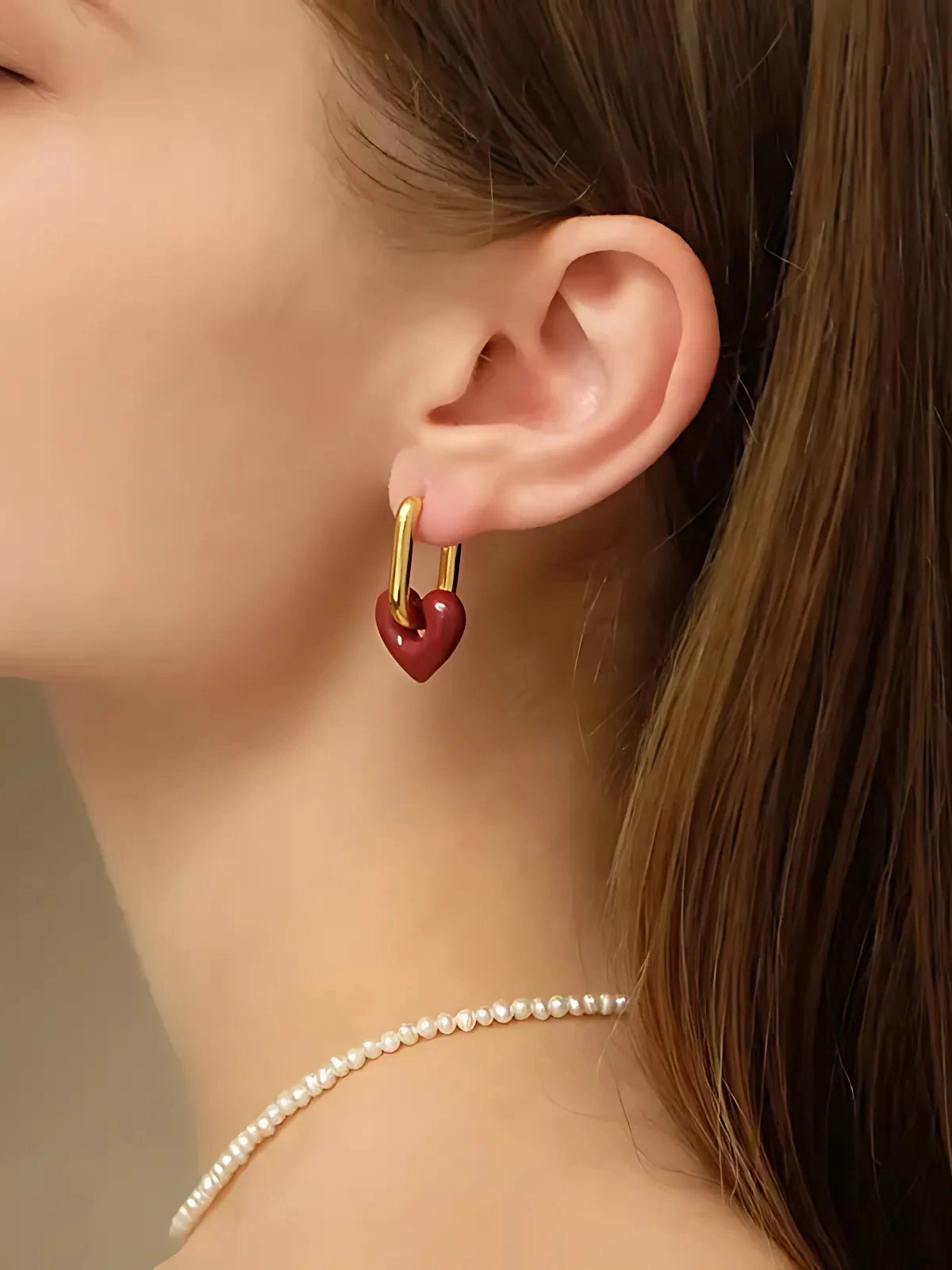 Sealed With Love Earring – On Ear Styled Shot-Close-up of a person wearing a gold earring with a red heart charm.