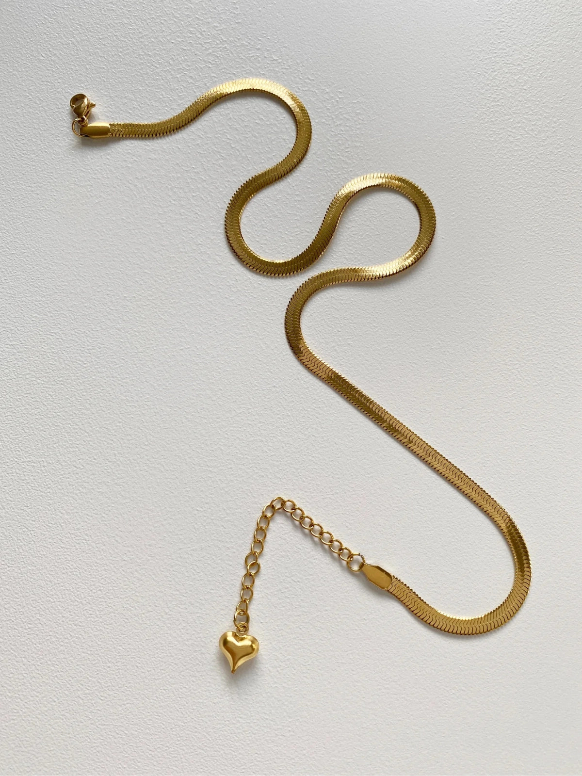 Slinka Chain – Close‑Up Detail-Gold snake chain necklace on a light gray background