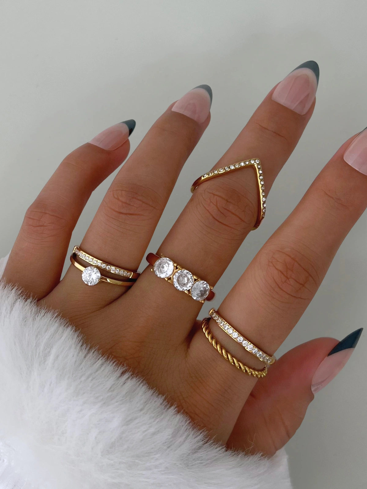 Sophisticate Ring – Worn on Finger-Hand wearing multiple gold and diamond rings on a neutral background