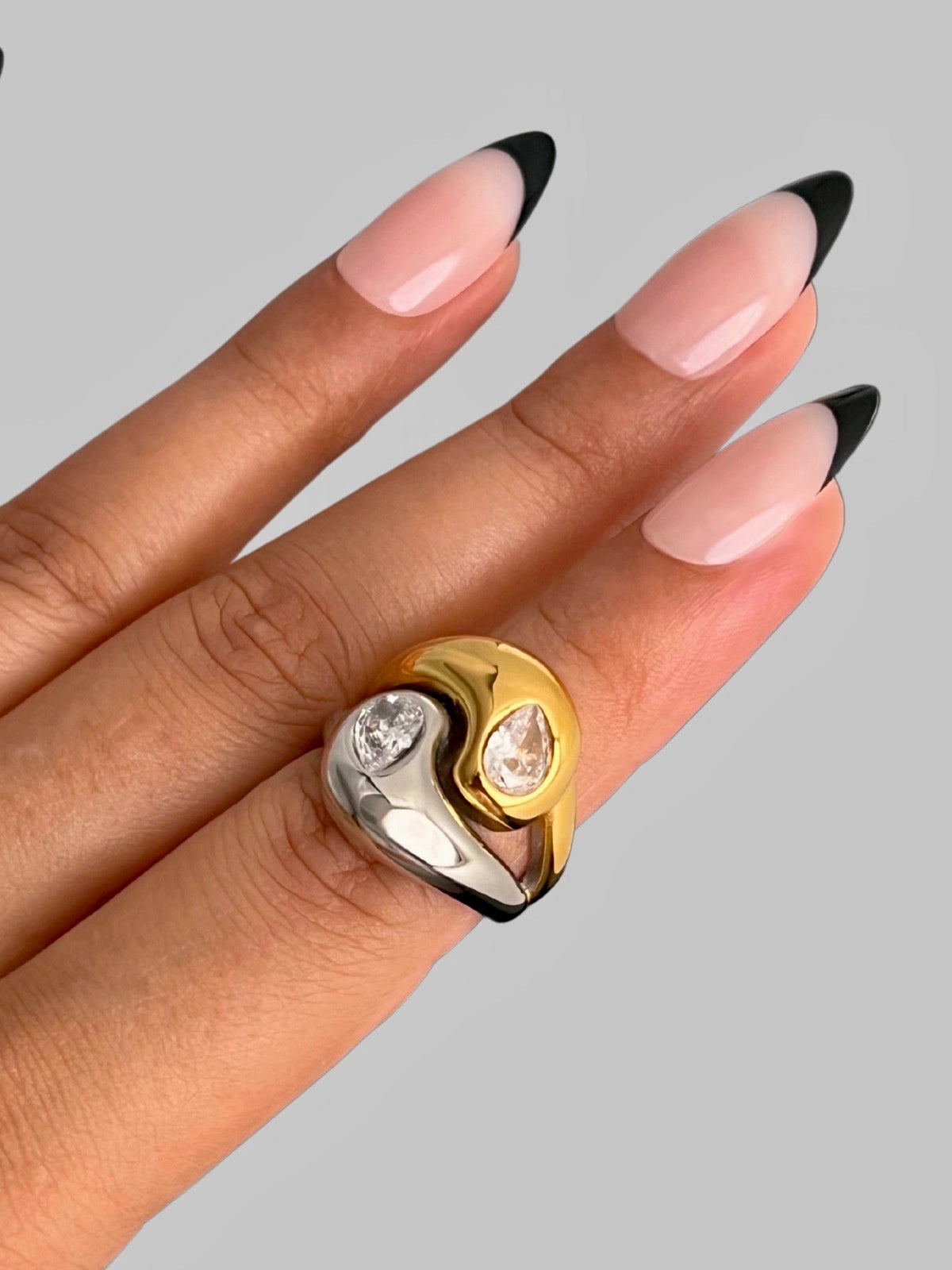 Starlet Ring | Shine With Me Gold and silver ring on a hand with pink nails against a gray background