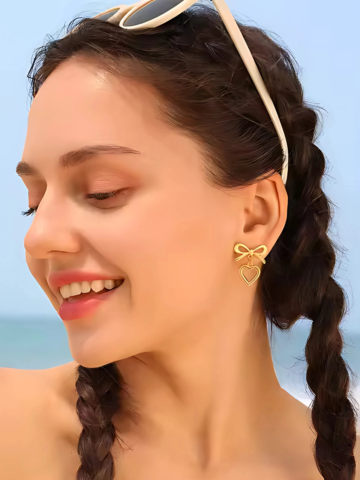 Stefani Bow Earring worn on ear — 18K gold‑plated stainless steel bow‑design by Shine With Me, styled for chic effect-Woman wearing gold bow-shaped earrings with a blurred background