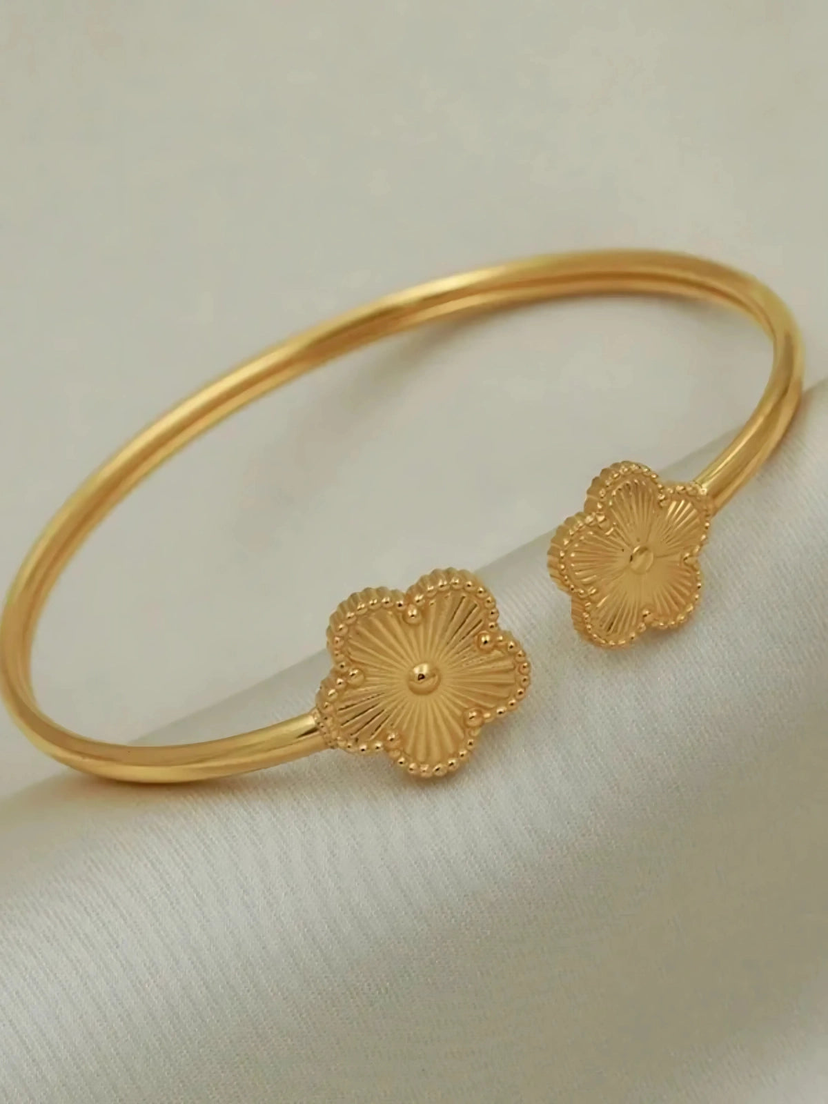 Sunveil Bangle Gold bracelet with floral designs on a light background