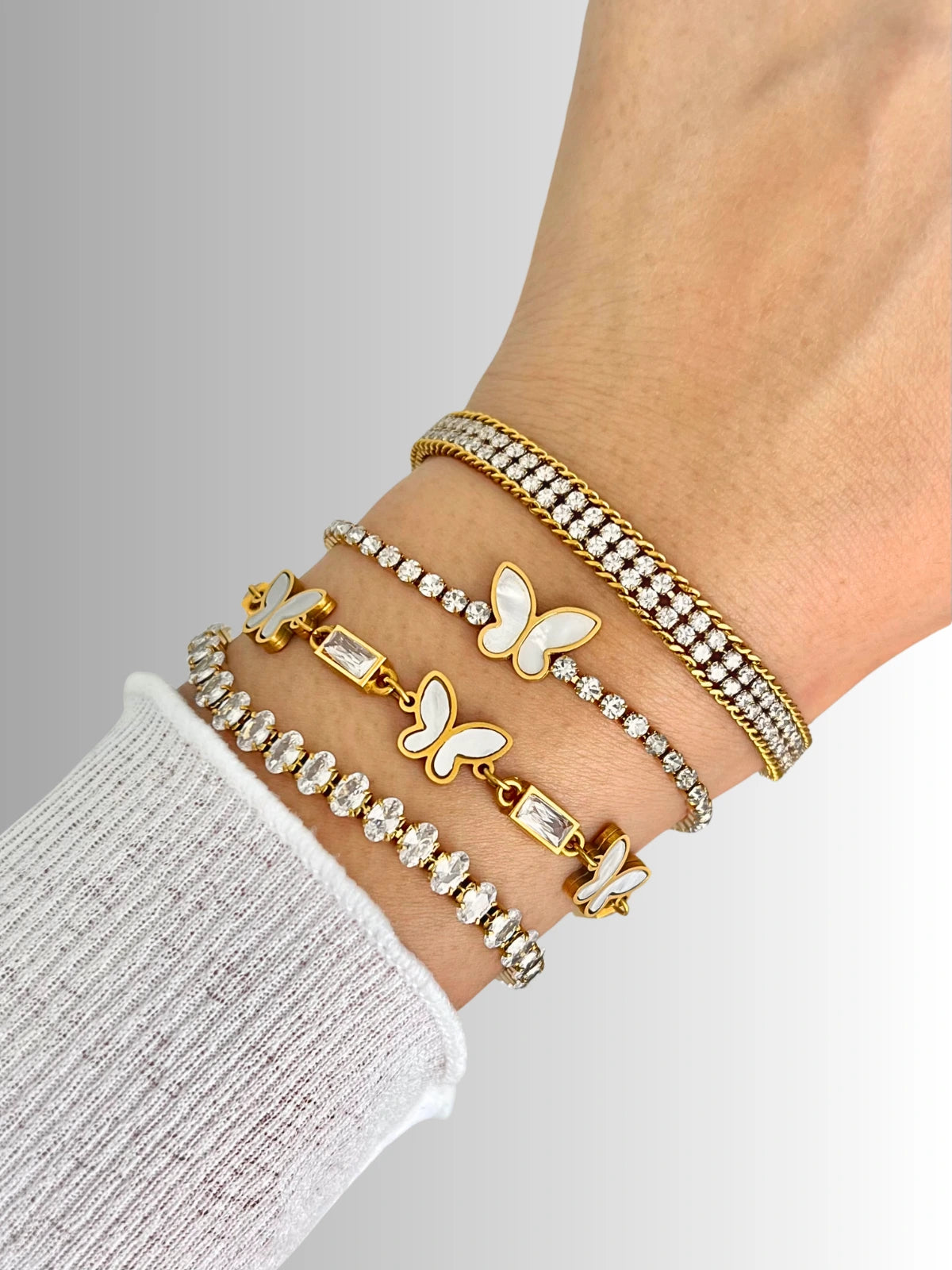 Sway Bracelet – On Wrist-Gold butterfly-themed bracelets on a wrist against a neutral background