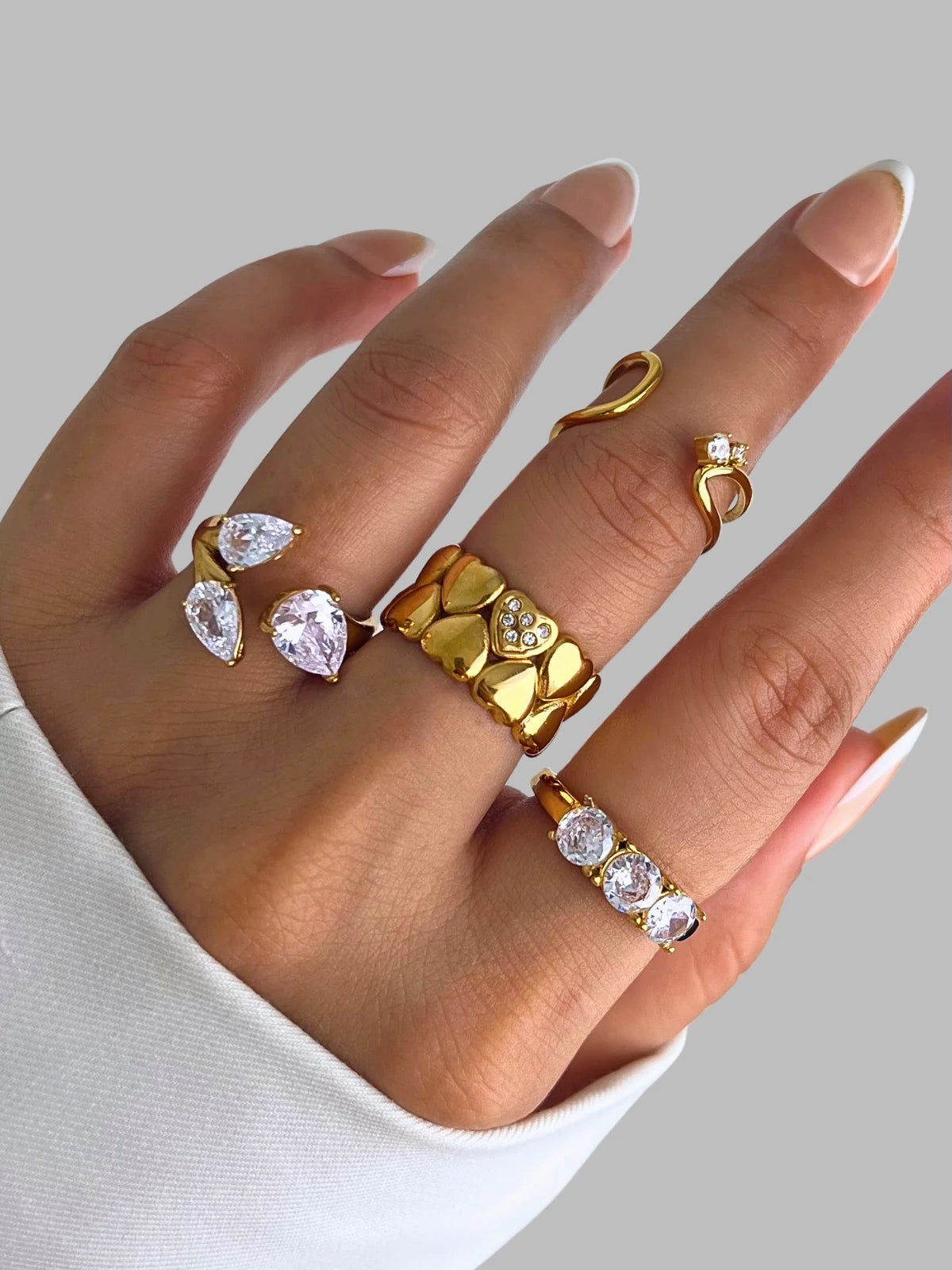 The Astria Ring – Close-Up Detail-Hand wearing multiple gold and diamond rings on a neutral background