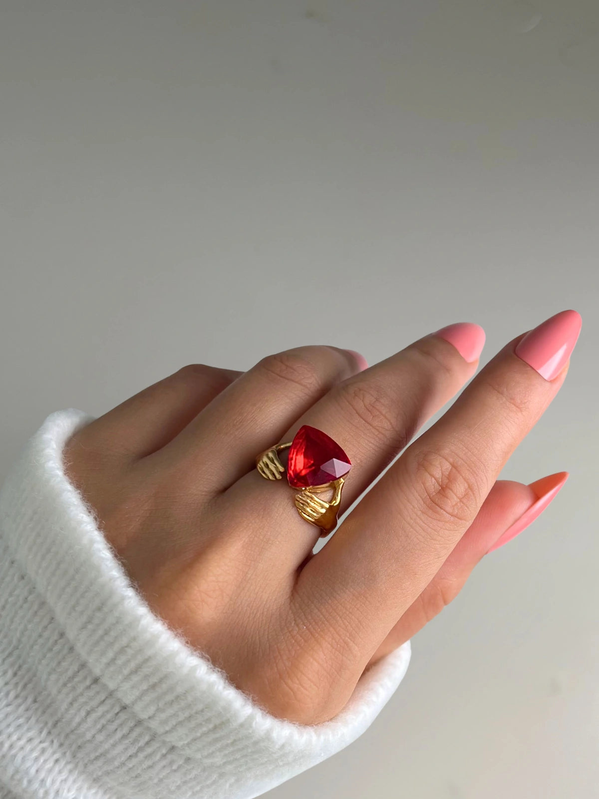 Vivienne Ring – On Model Styled Shot-Hand wearing a gold ring with a red gemstone on a plain background