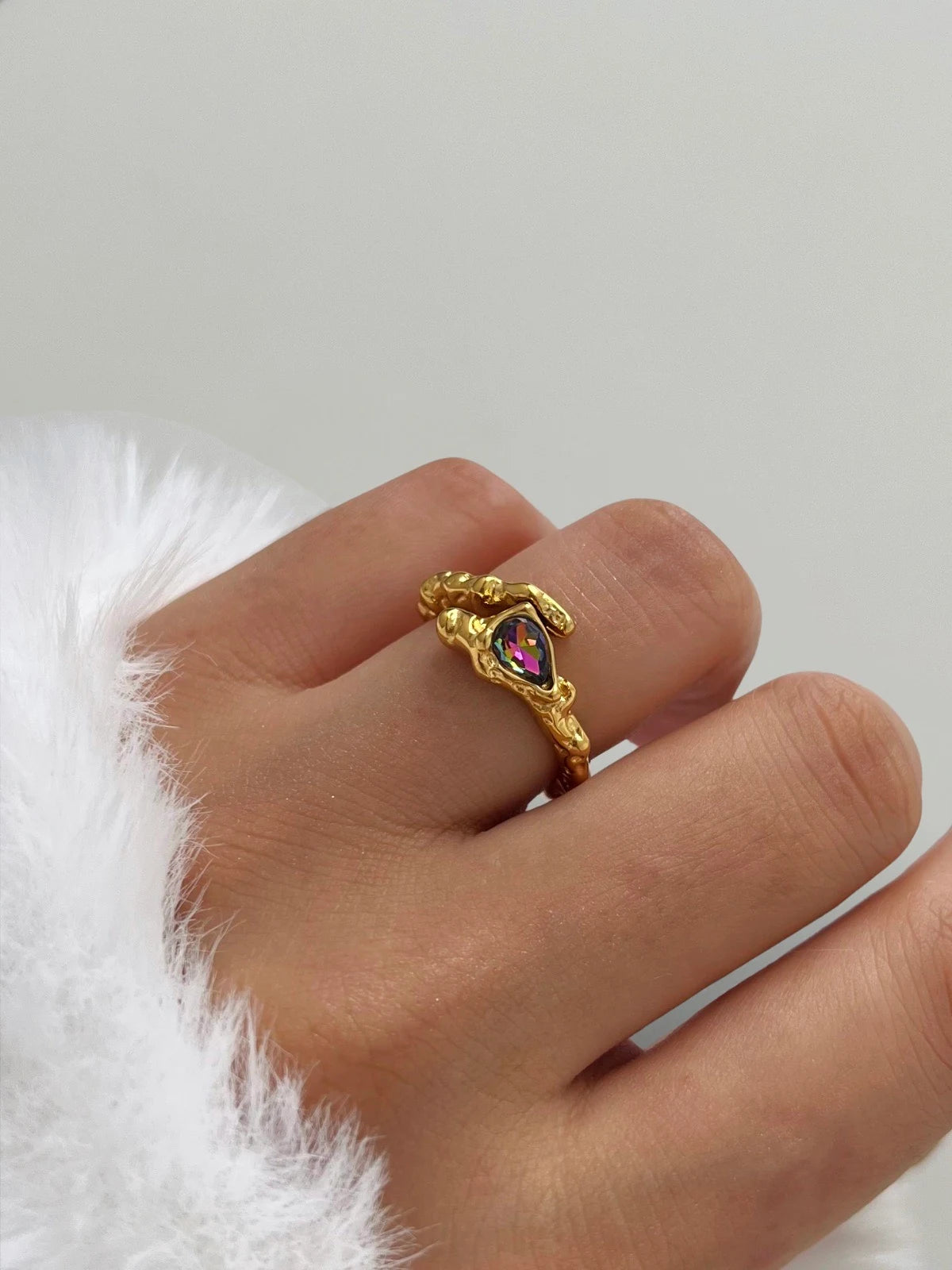 Voss Ring – Worn on Finger-Gold ring with a colorful gemstone on a finger against a white background