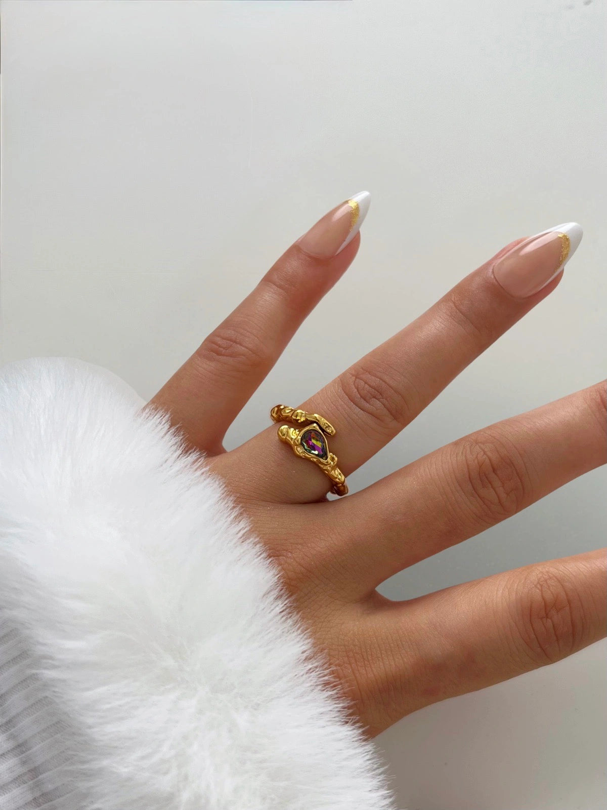 Voss Ring – Worn on Finger-Gold ring with a gemstone on a finger against a white background