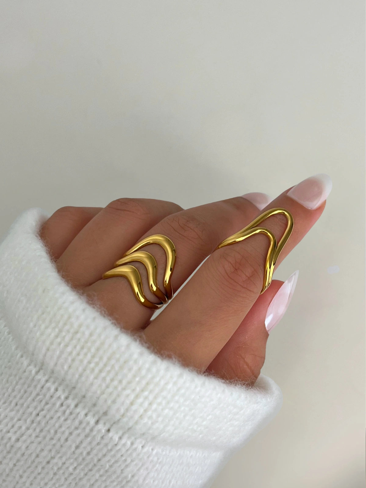 ameline-ring-side-angle-shine-with-me. Gold ring on a finger with a plain background