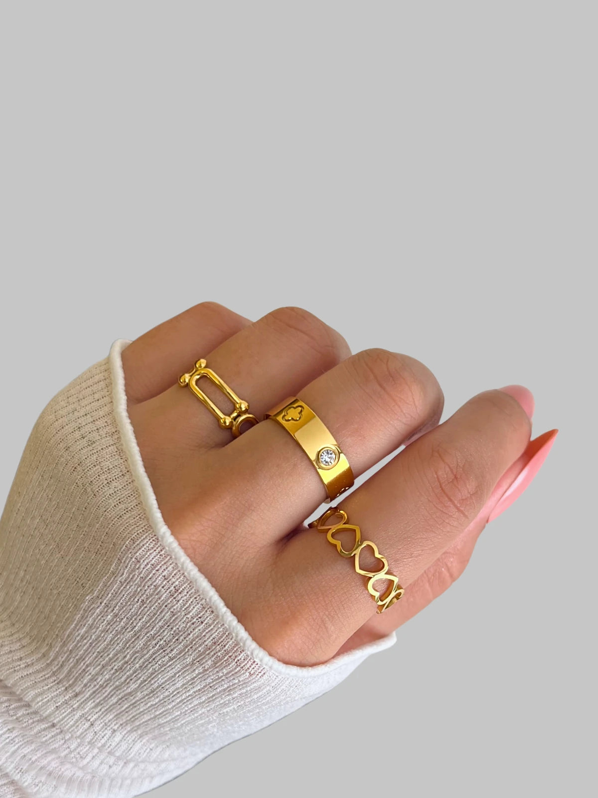 daily-rings-front-view-shine-with-me Hand wearing gold rings with a plain background