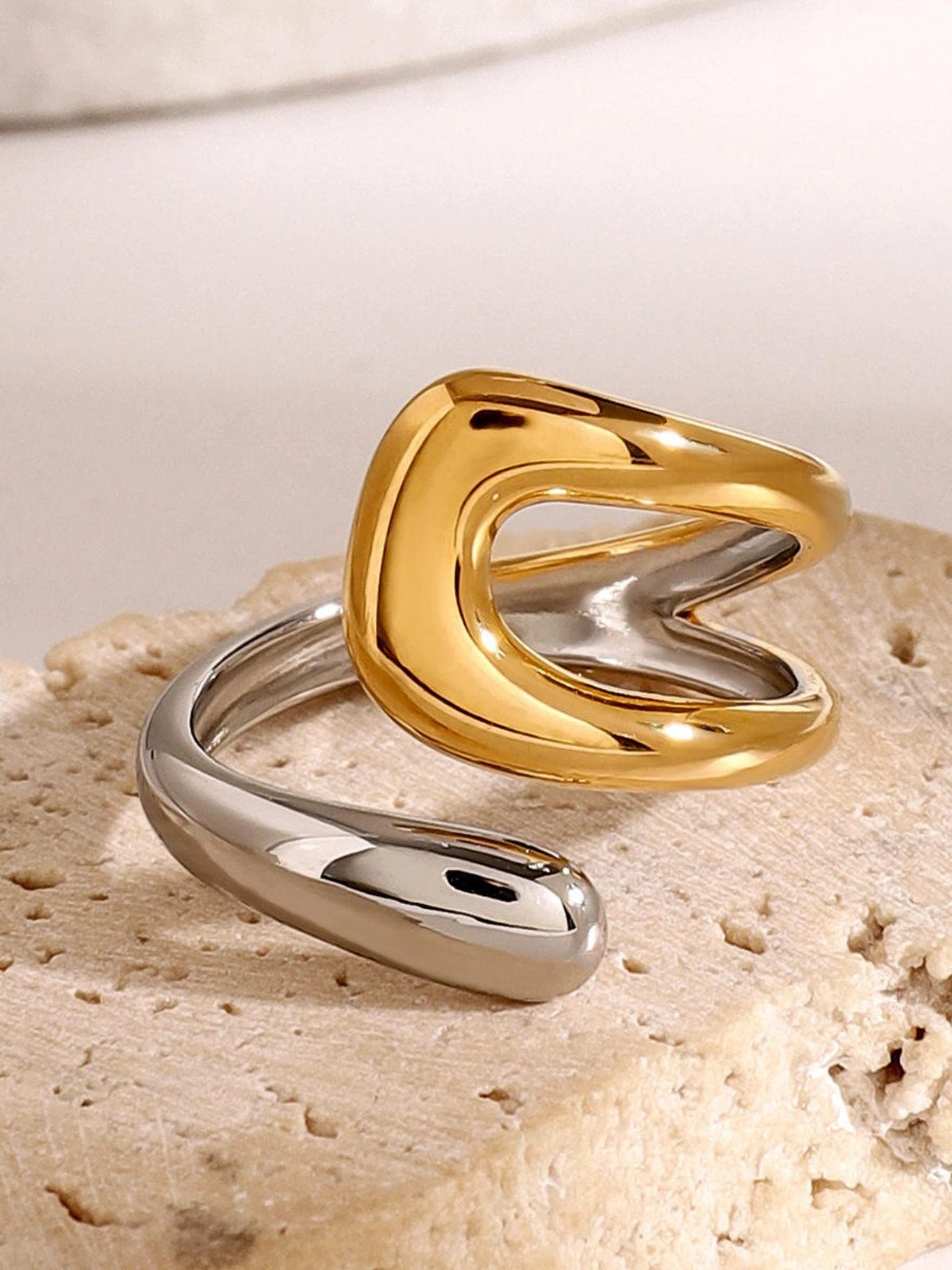 seaborn-ring-lifestyle-shot-shine-with-me.Gold and silver ring set on a textured beige surface